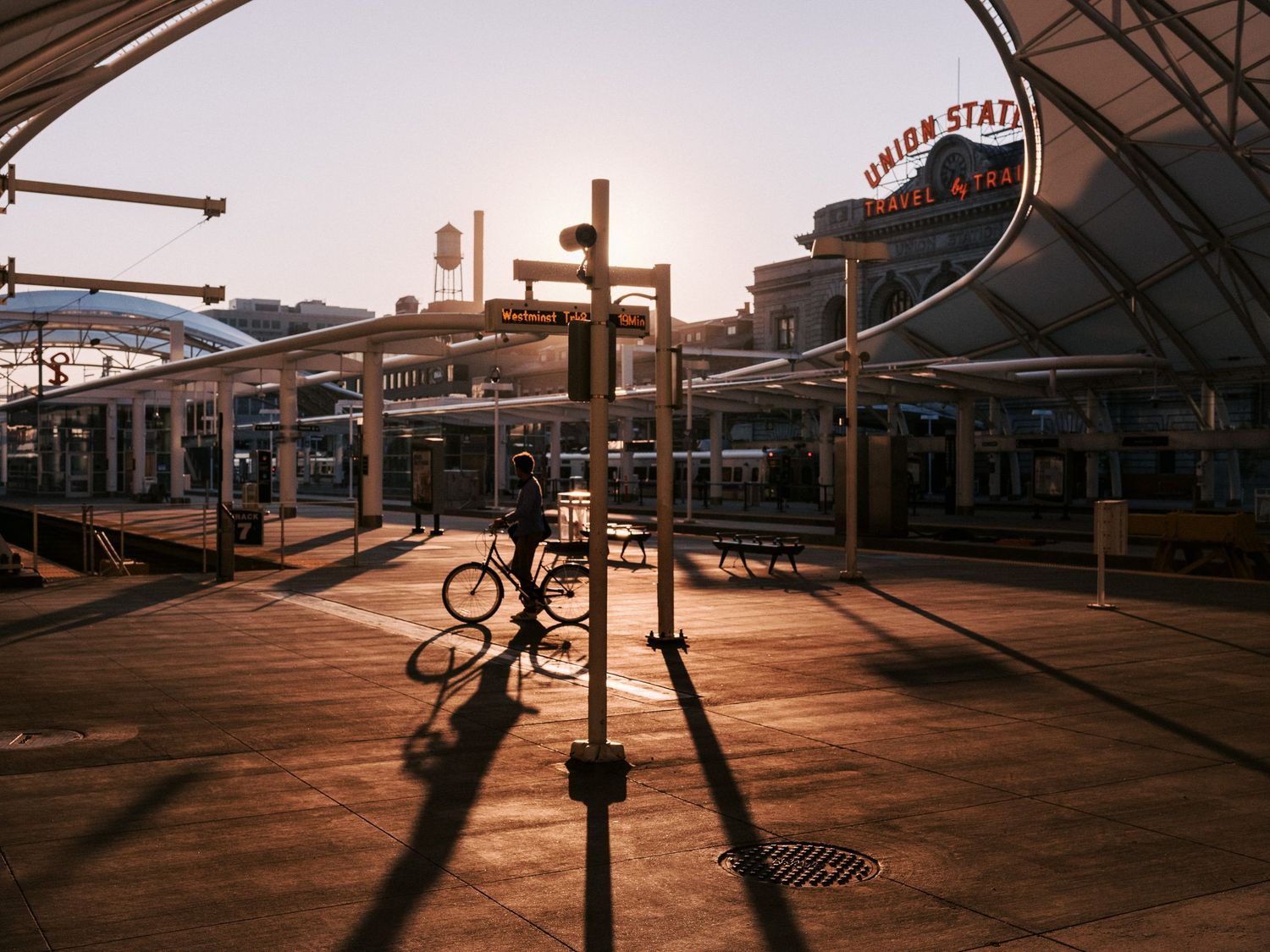 Silhouetted figures cast long shadows on a boardwalk during sunset creating a dramatic panoramic scene.
