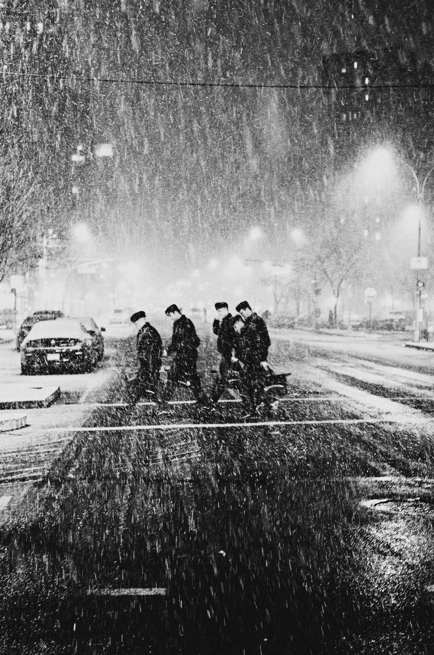 A group of people huddle in heavy snowfall at night on what appears to be a road or pathway.