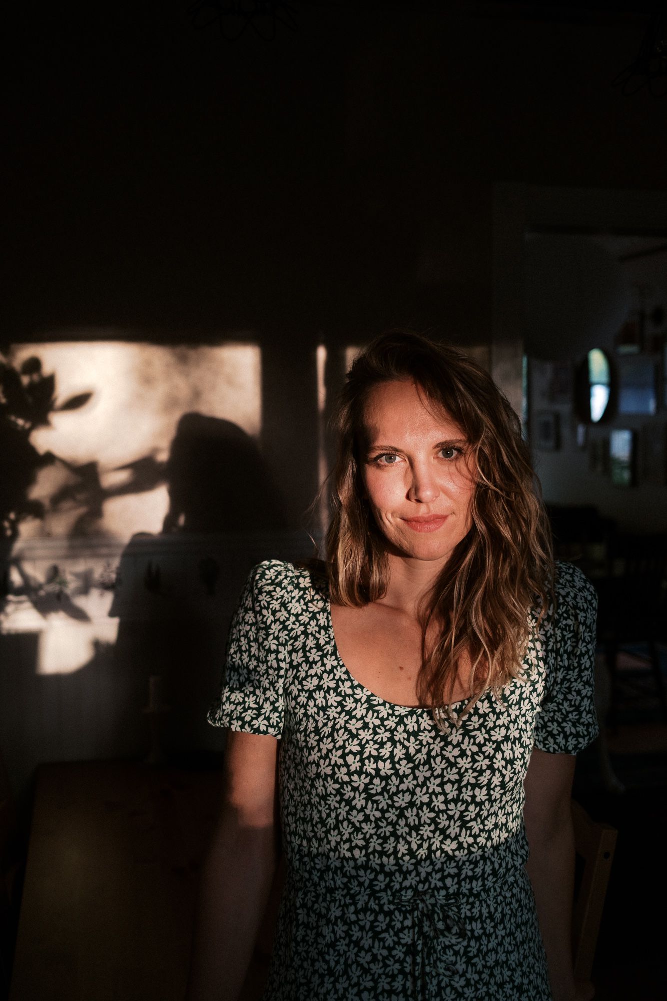 Low-key portrait in moody lighting with floral pattern dress.