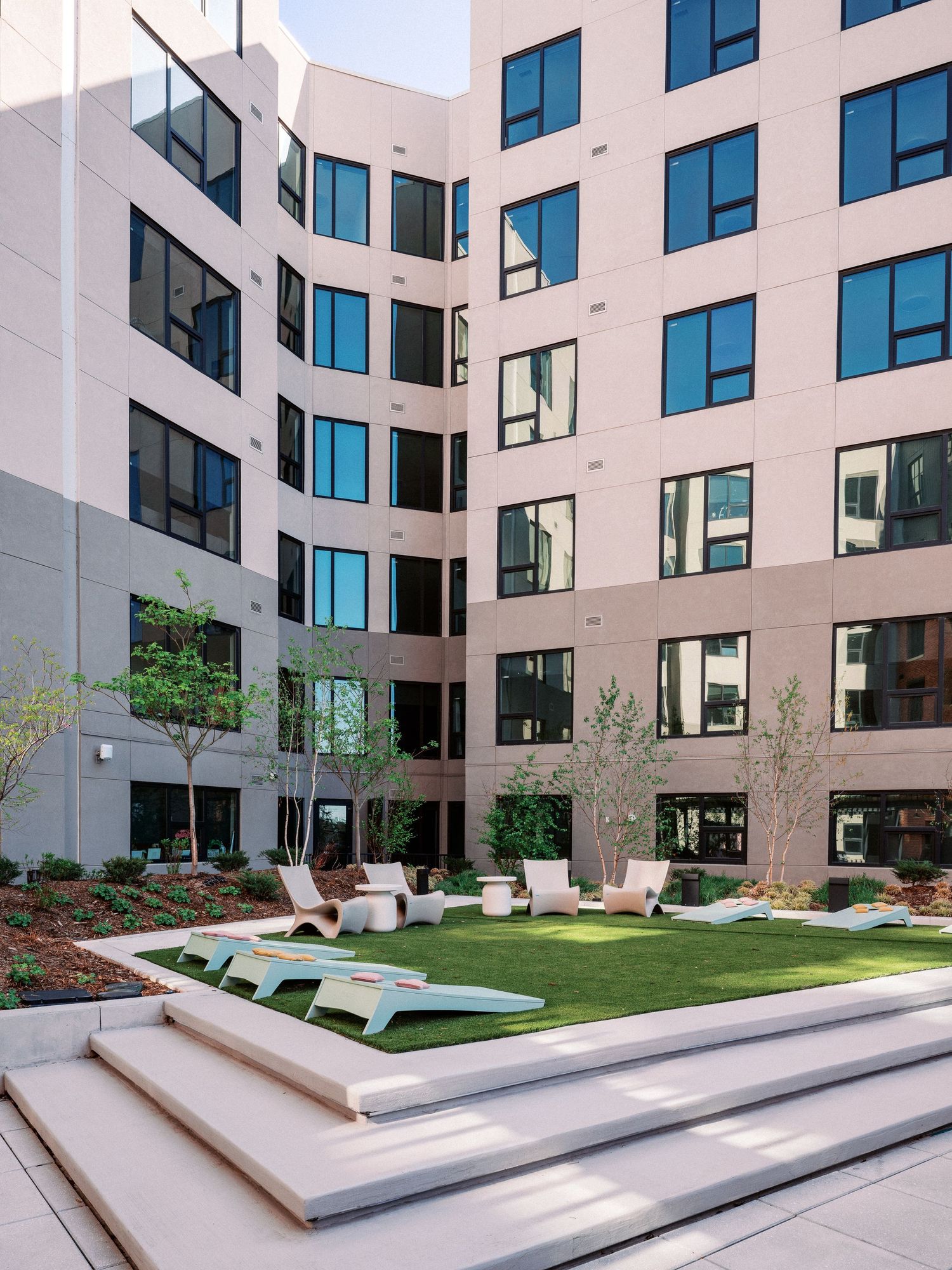 Modern apartment courtyard with tiered landscaping and lounge seating areas.
