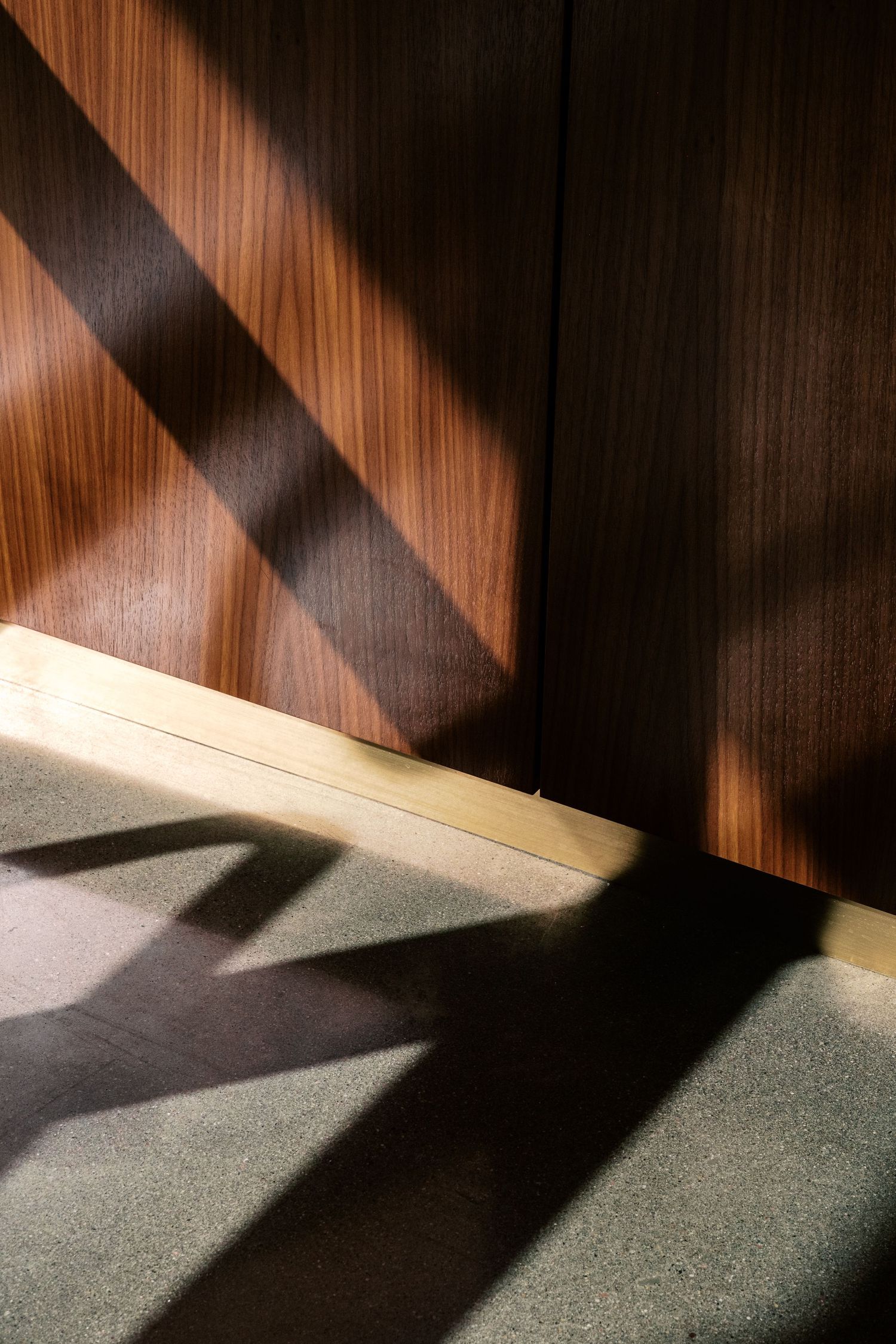 Dramatic shadows cast on wooden wall creating abstract geometric patterns.