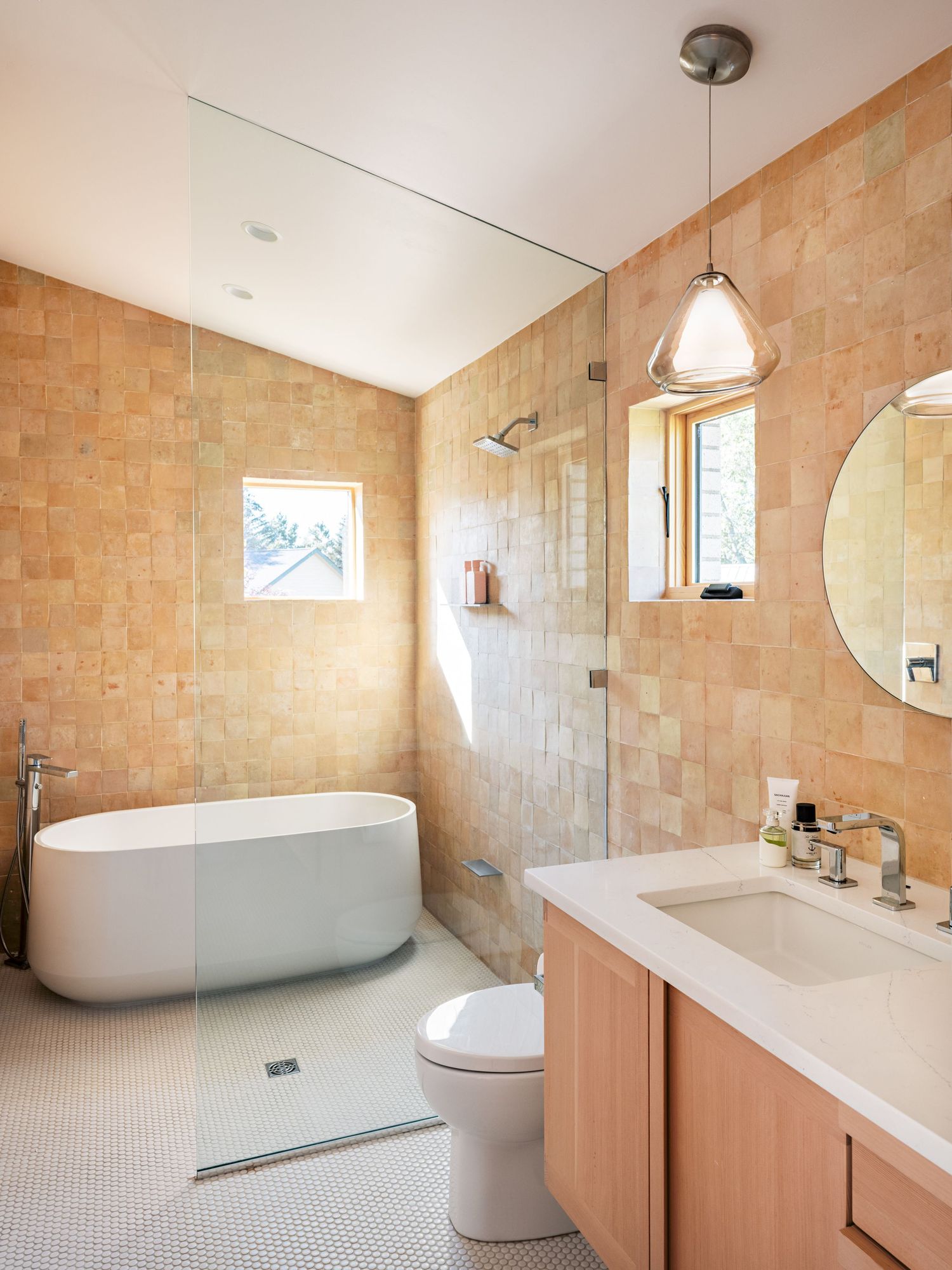 Luxurious bathroom featuring freestanding tub and beige tile walls with modern fixtures.