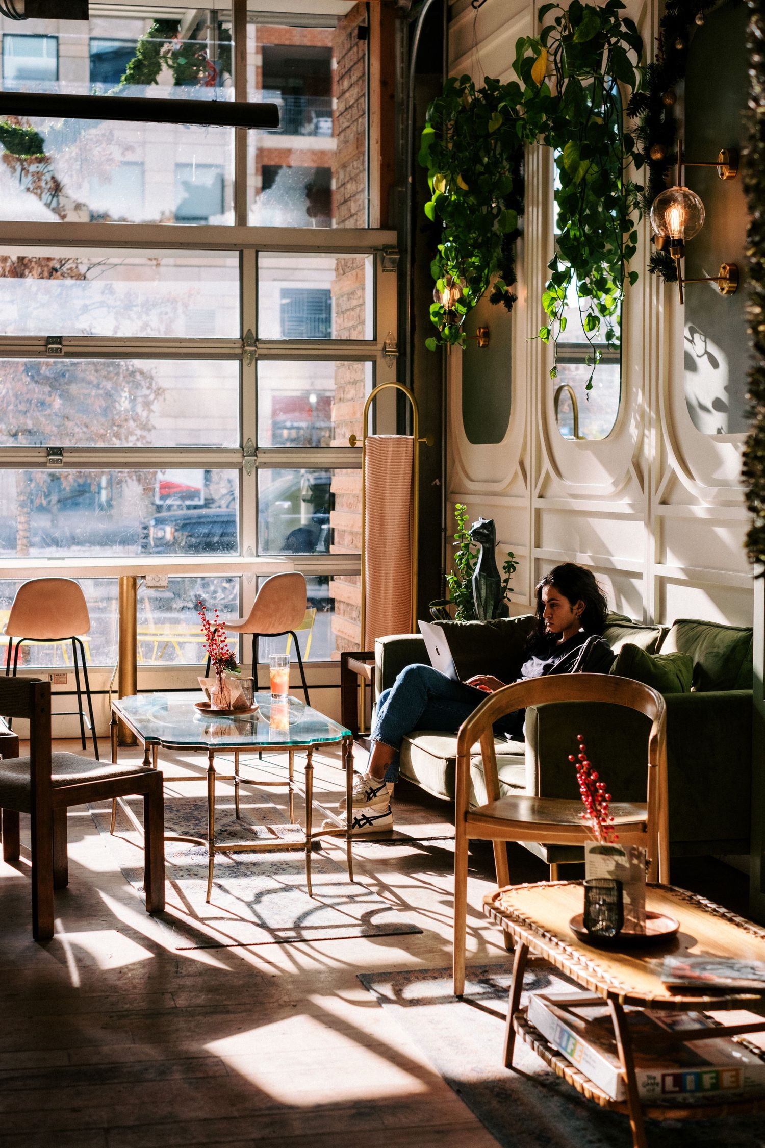 Sunlit cafe interior with modern furniture and large windows.