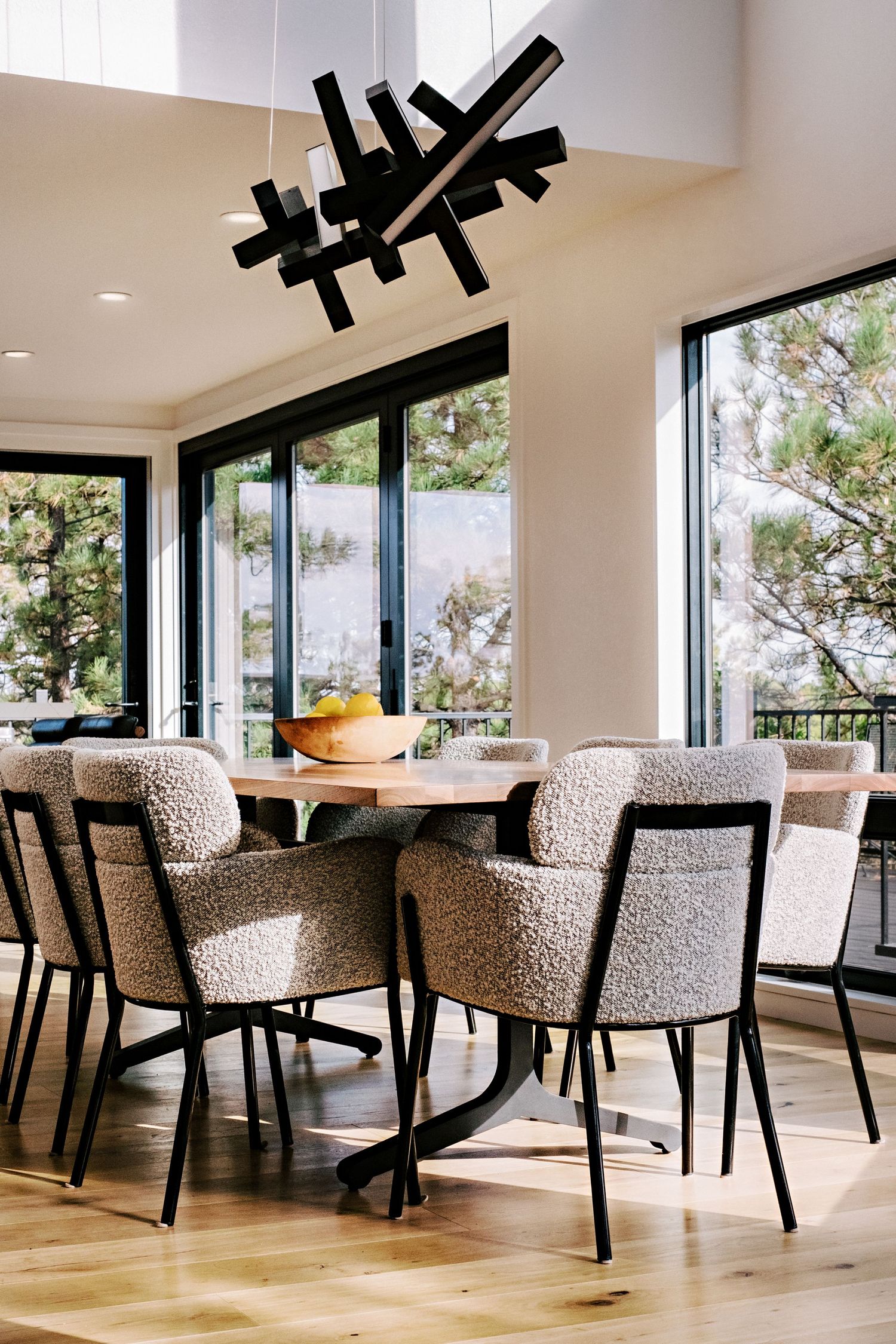 Elegant dining space with textured upholstered chairs and wooden table overlooking mountain views.