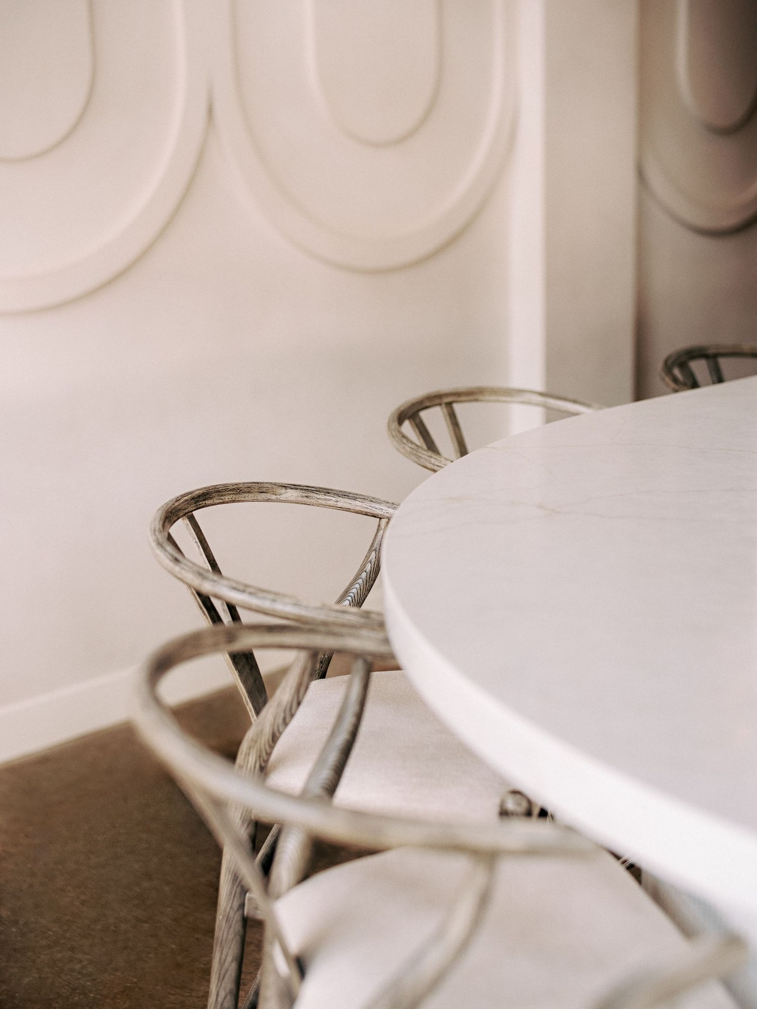 Close-up of white dining tables with modern silver chairs against a clean white wall.