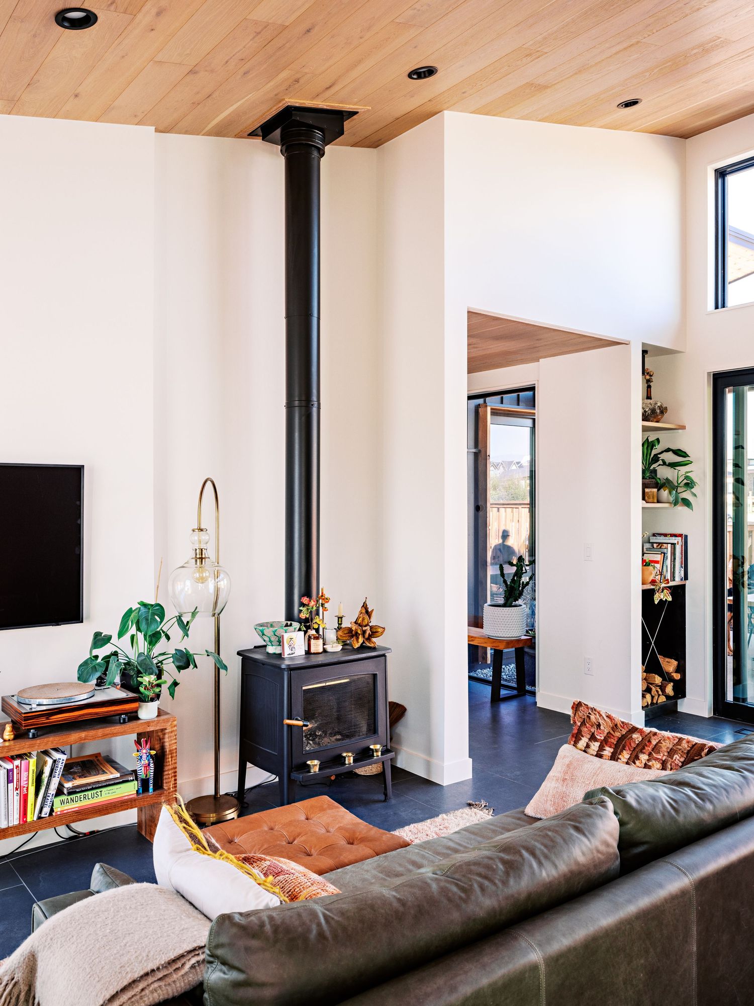 Contemporary living room with grey sectional sofa, wood floors, and large windows letting in natural light.
