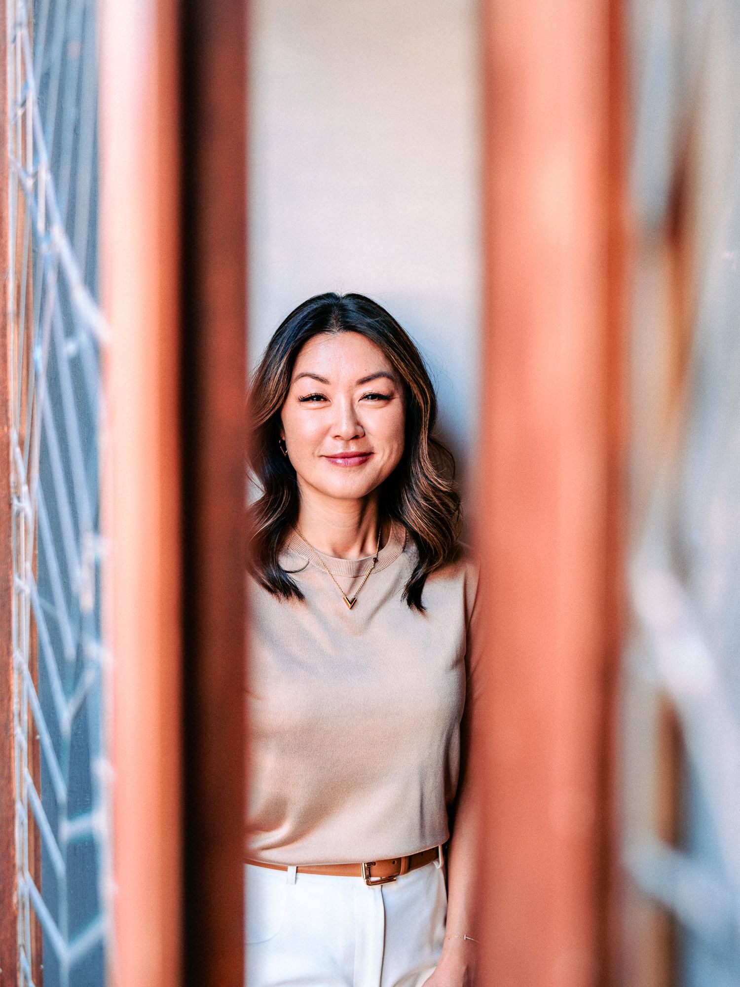 Portrait in a hallway with coral-colored pillars creating a repeating pattern effect.