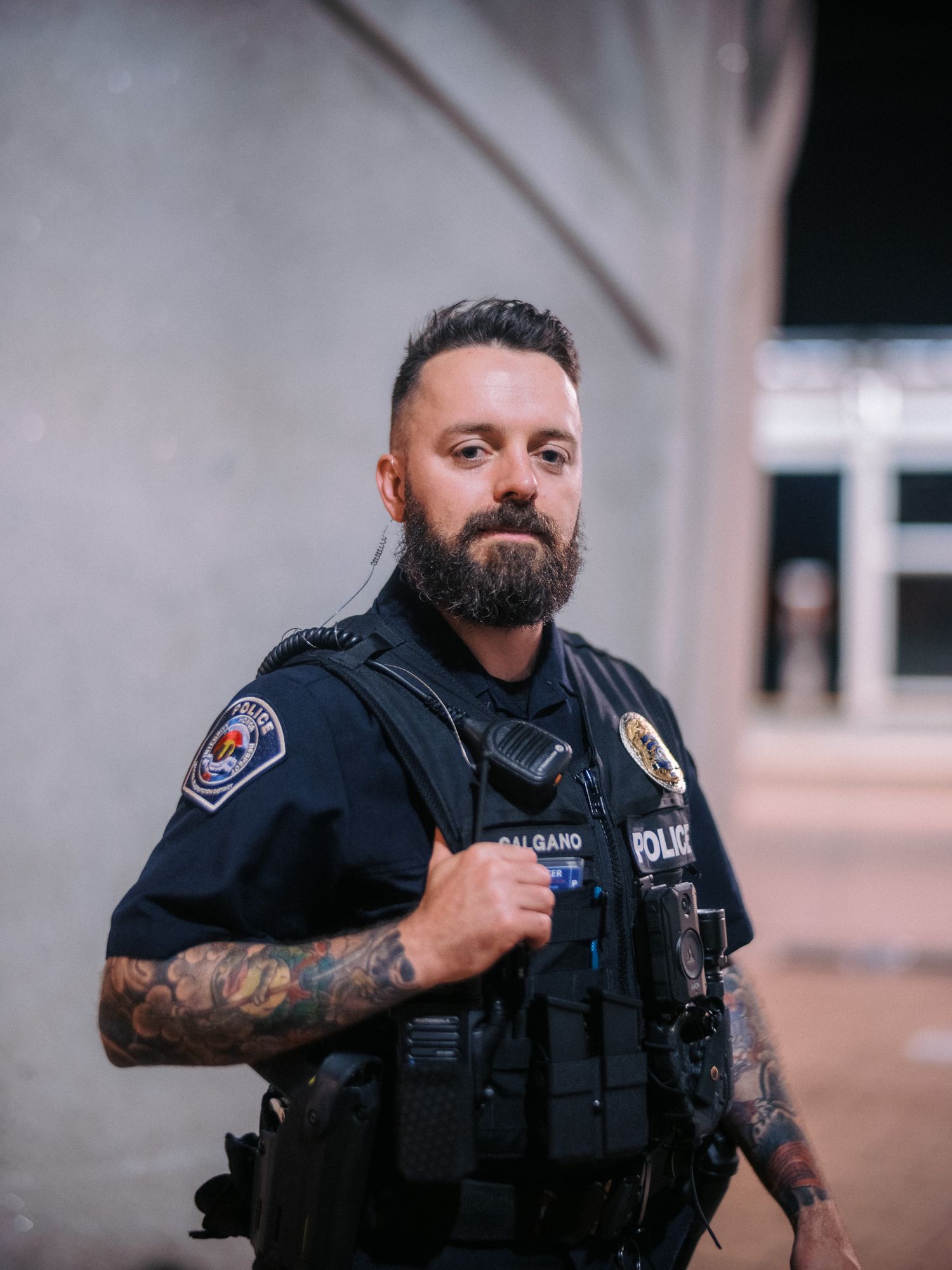 Law enforcement officer in tactical gear with visible tattoos and equipment.