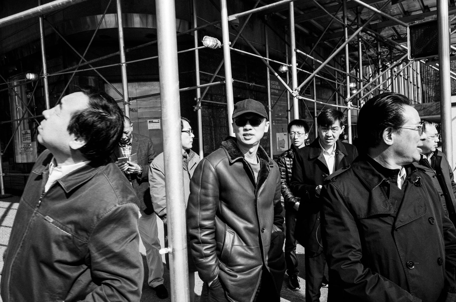 A black and white photograph shows a crowded subway platform with commuters waiting during rush hour.
