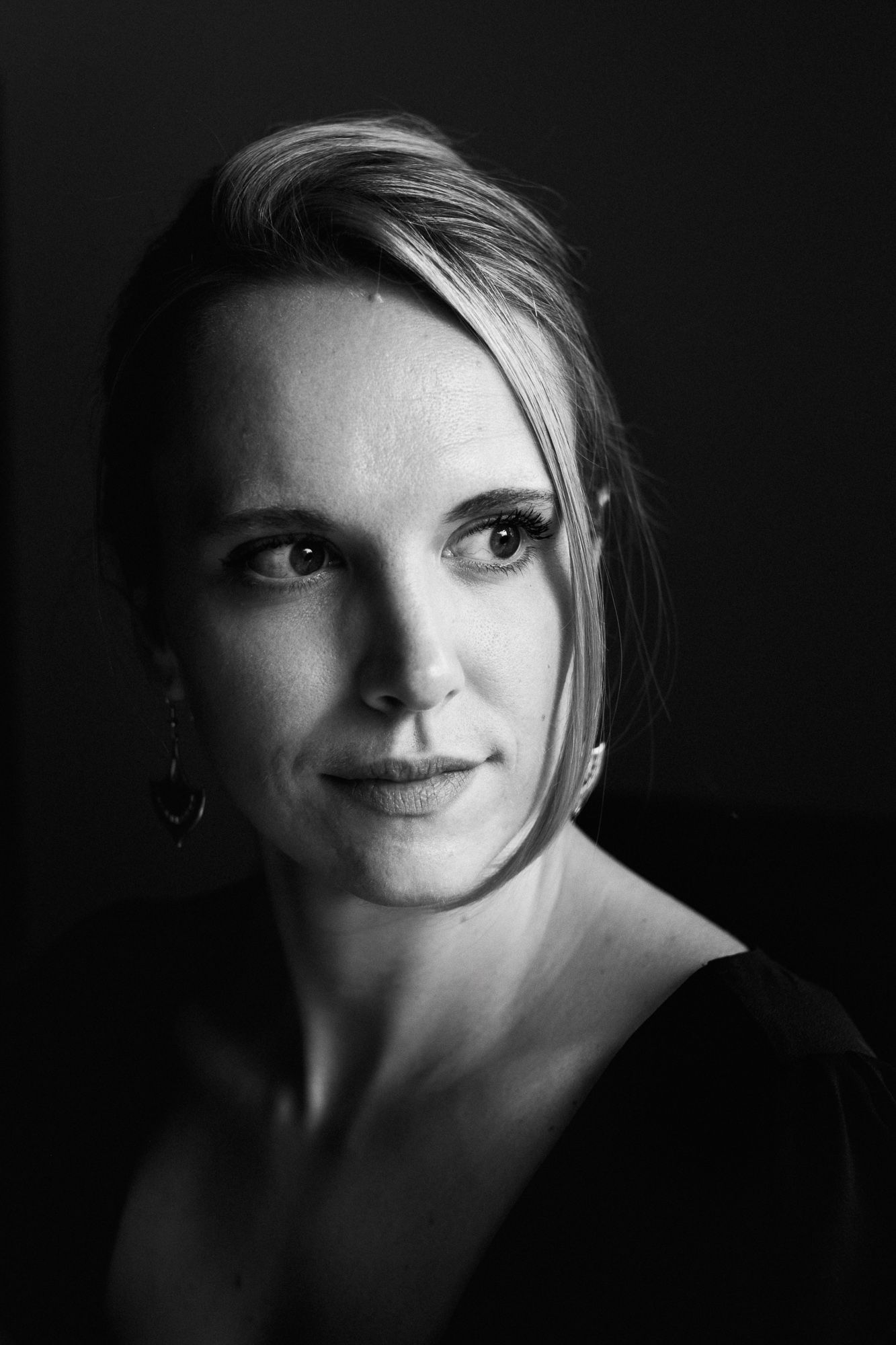 Close-up black and white portrait showing half of a face with dramatic side lighting.
