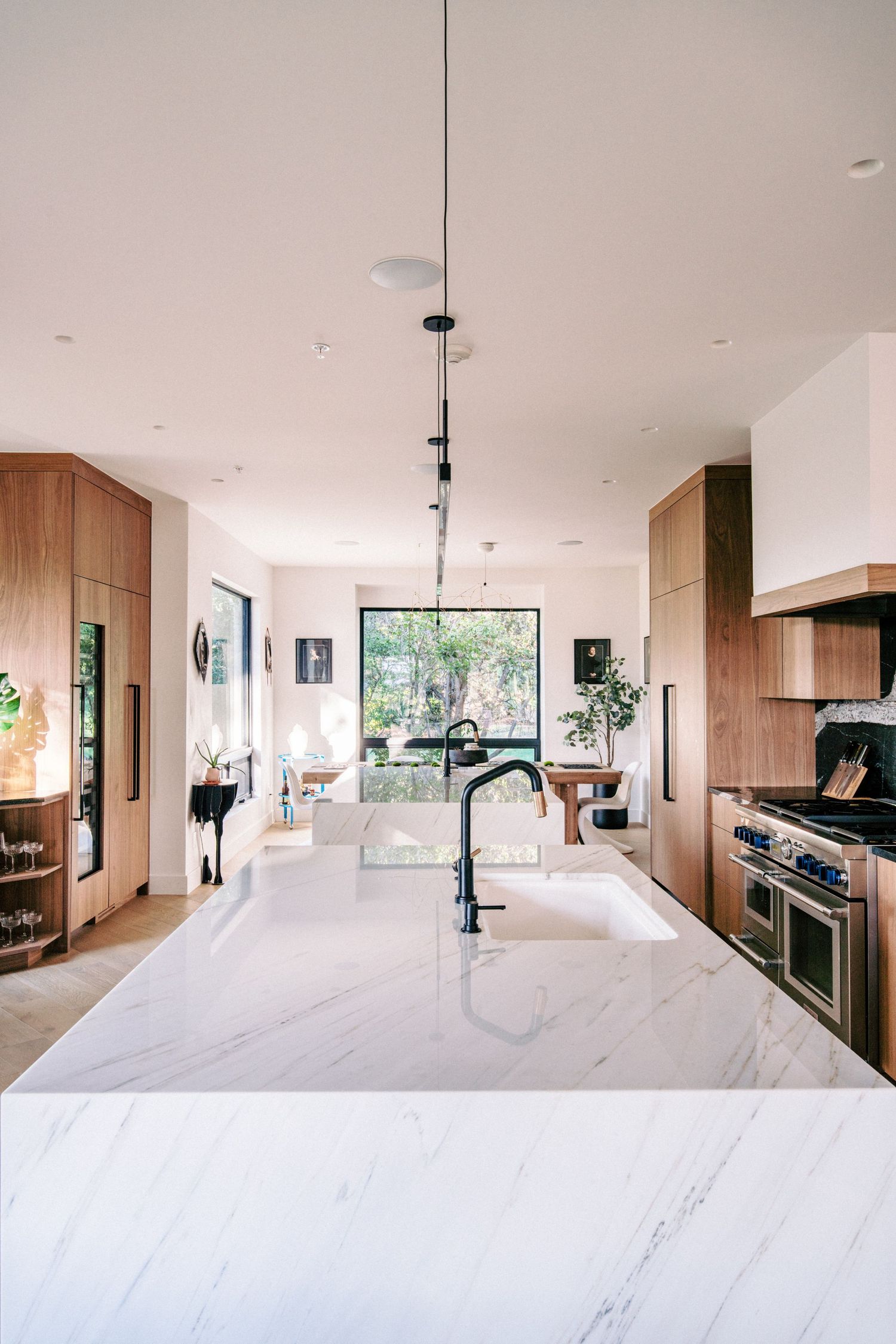 Modern kitchen with white marble countertops and large windows bringing in natural light.