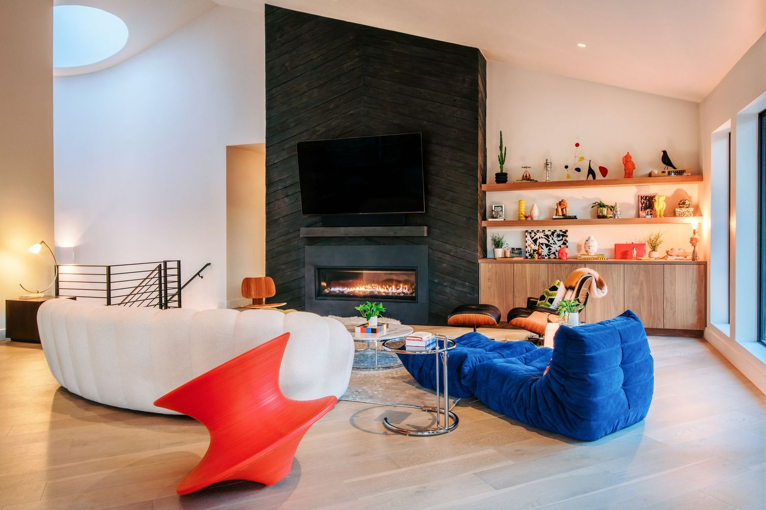Contemporary living room with black fireplace, blue bean bag chair, and modern red accent furniture.