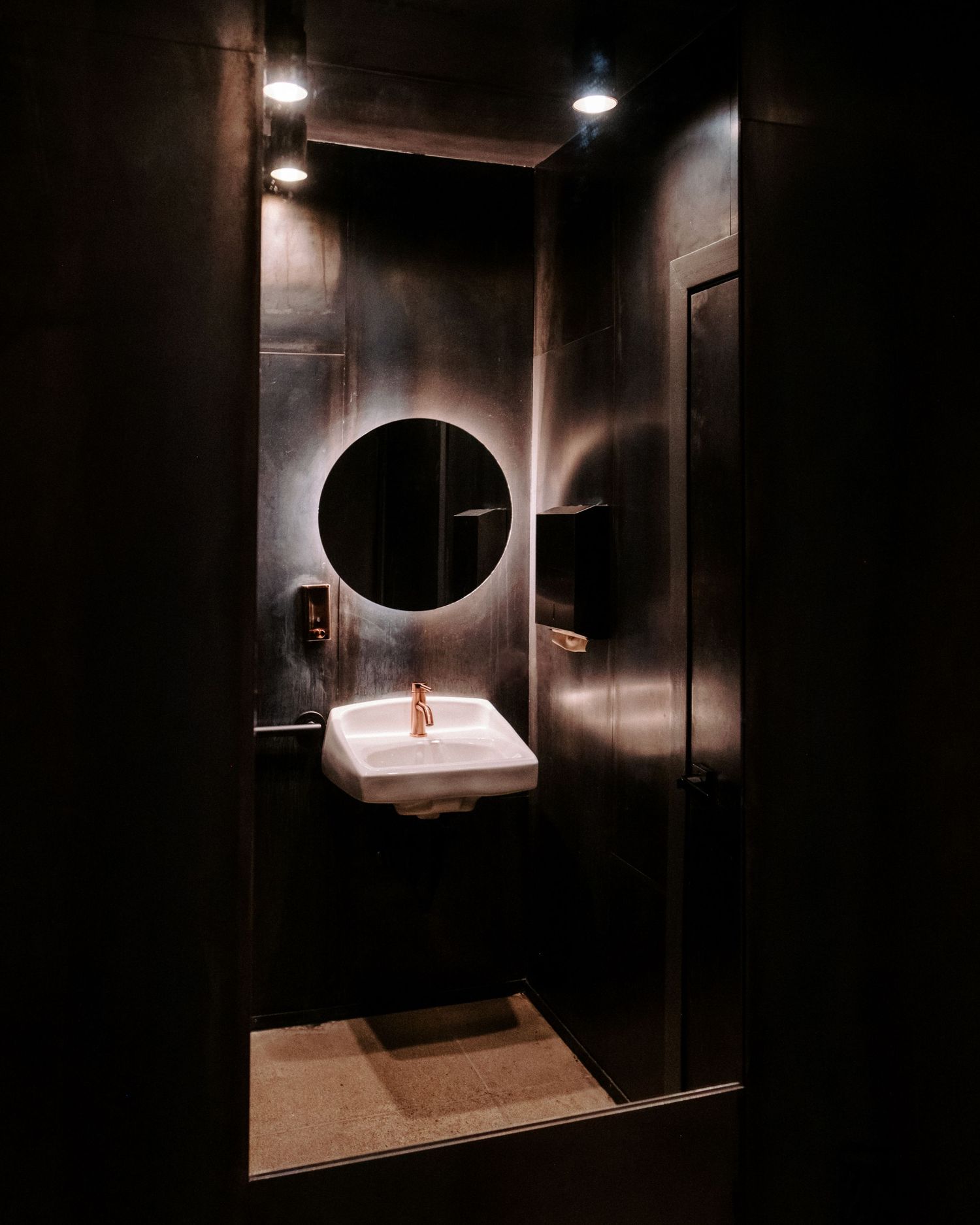 Minimalist dark room interior with circular window creating dramatic lighting and shadows.