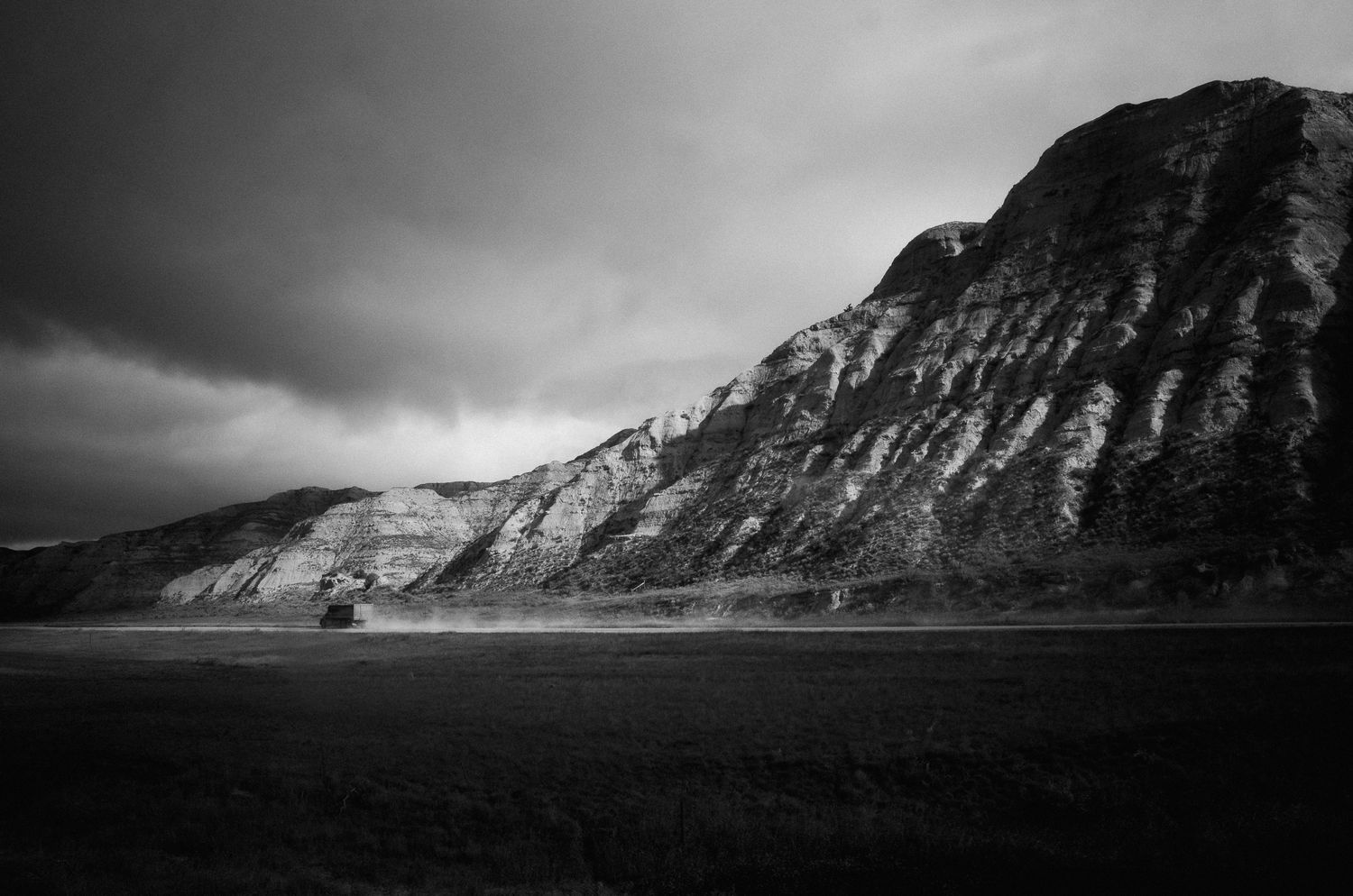 Dramatic black and white landscape of steep mountain cliffs under cloudy skies.