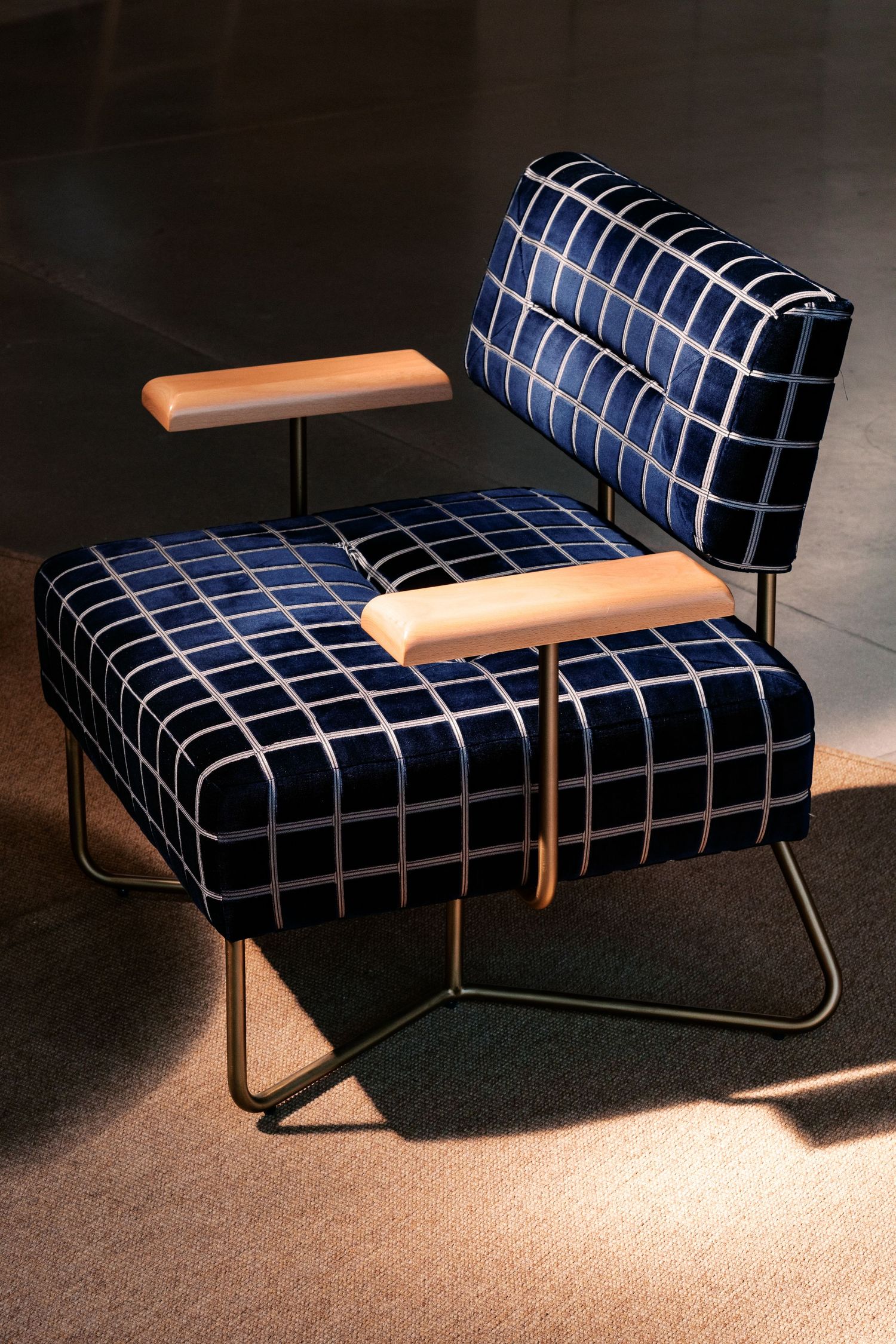 Modern chaise lounge with navy grid pattern upholstery and minimalist metal frame design.
