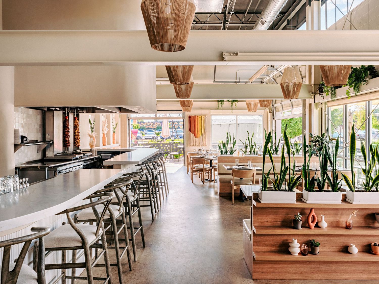 Spacious dining room with natural lighting, wooden tables, and decorative plants creating a warm ambiance.