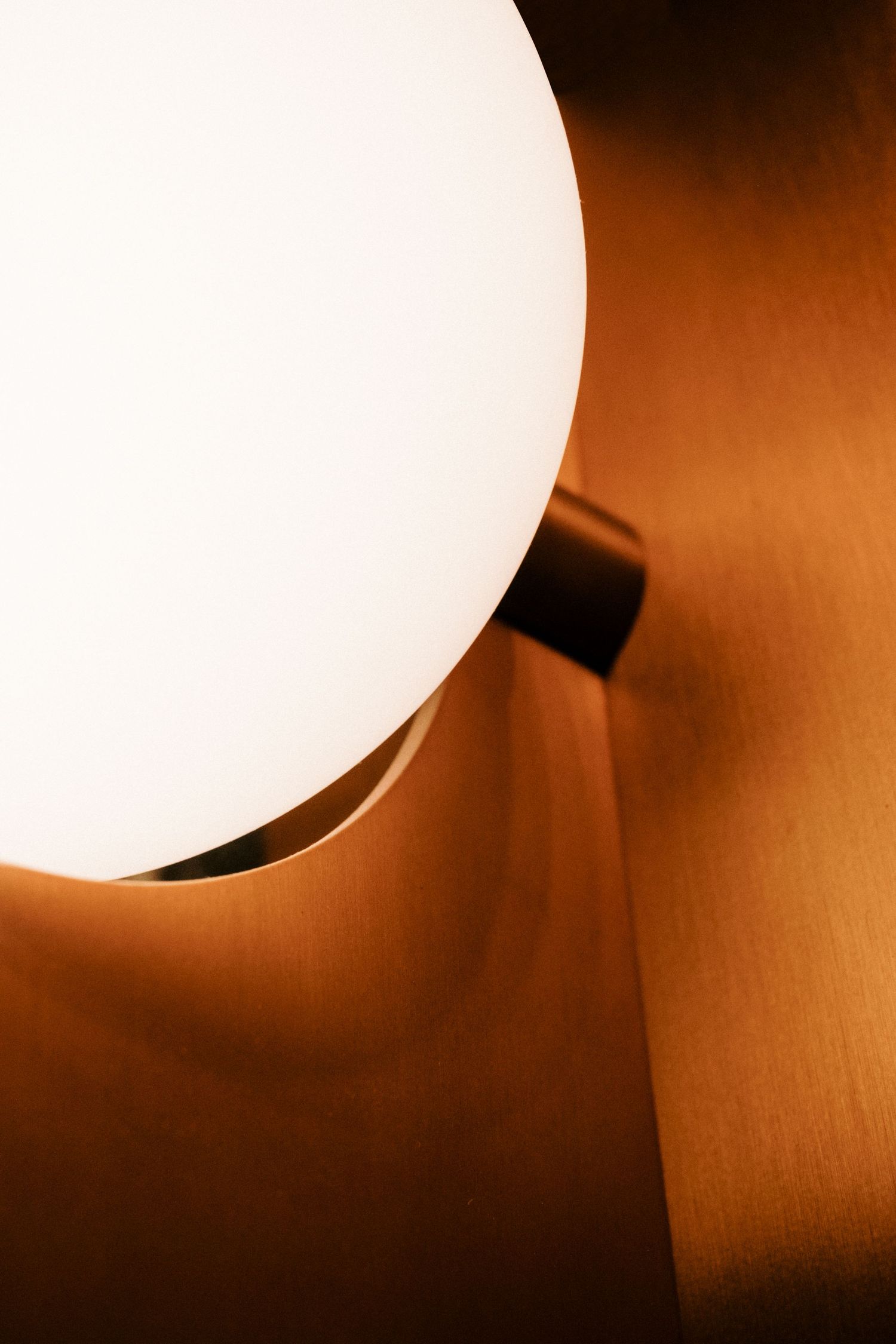 Glowing spherical light fixture creating warm ambient lighting against orange wall.