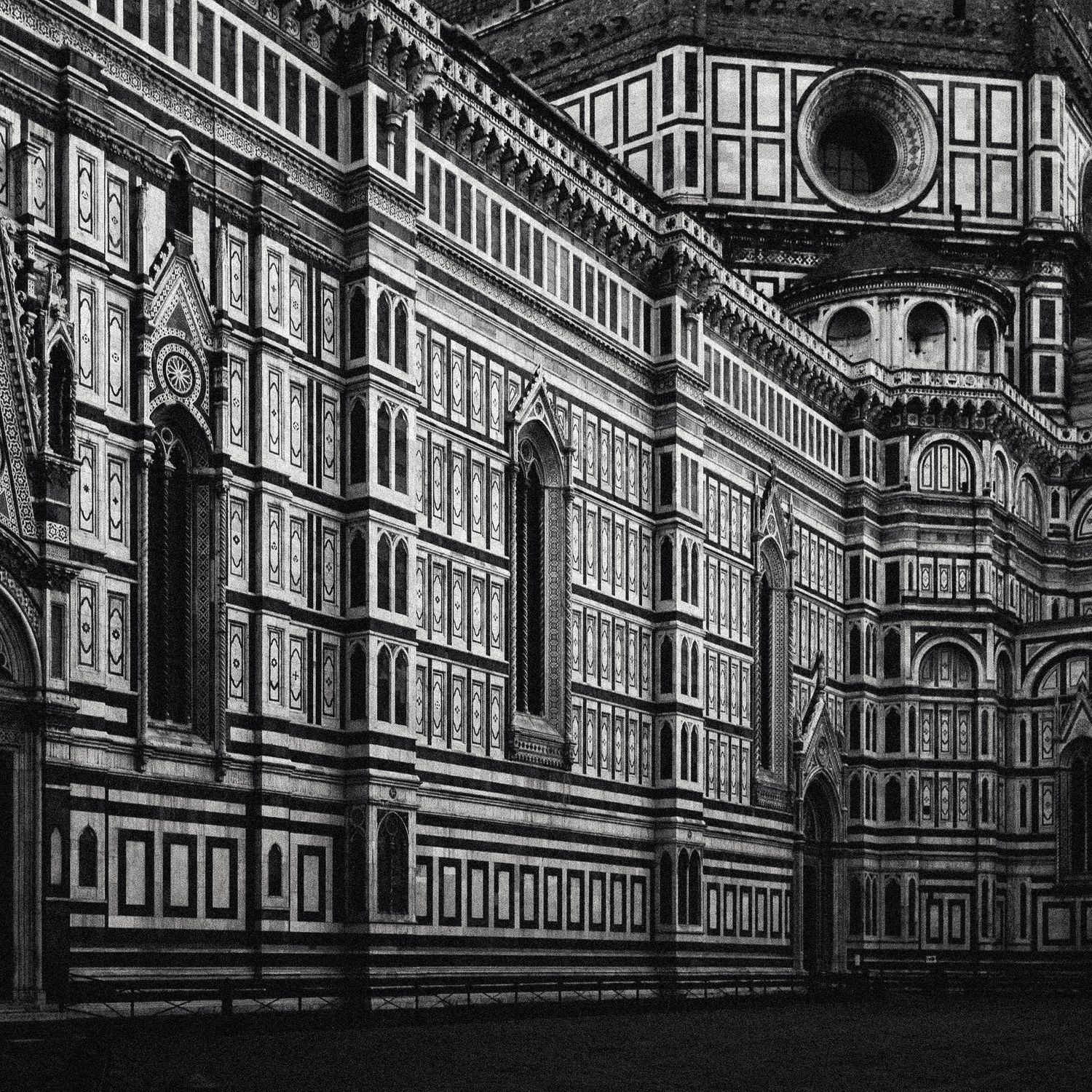 Black and white architectural photograph of the ornate facade of Florence Cathedral with dramatic shadows and details.