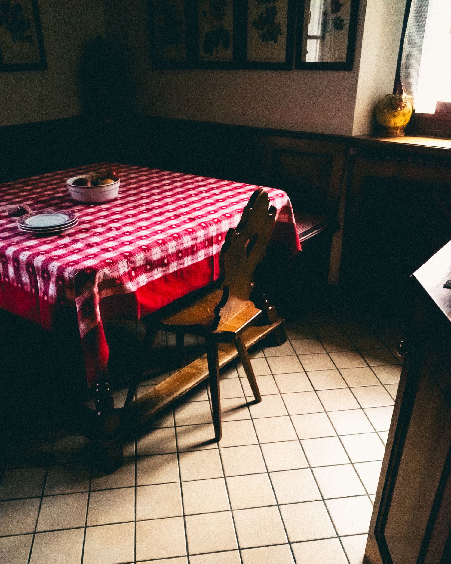Restaurant interior with red and white checkered tablecloths on wooden tables in a dimly lit room.