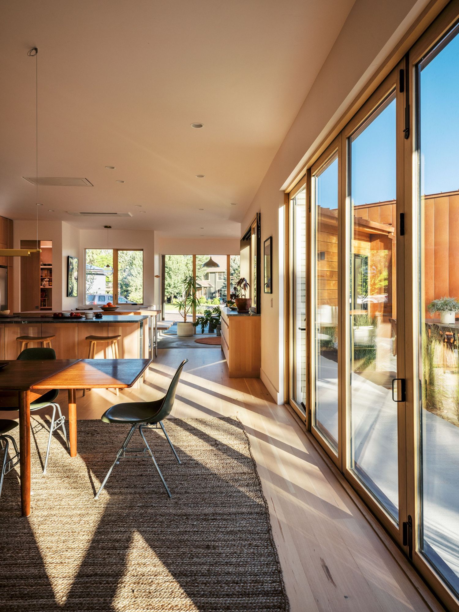 Spacious living area with floor-to-ceiling windows casting dramatic shadows across carpeted floor.