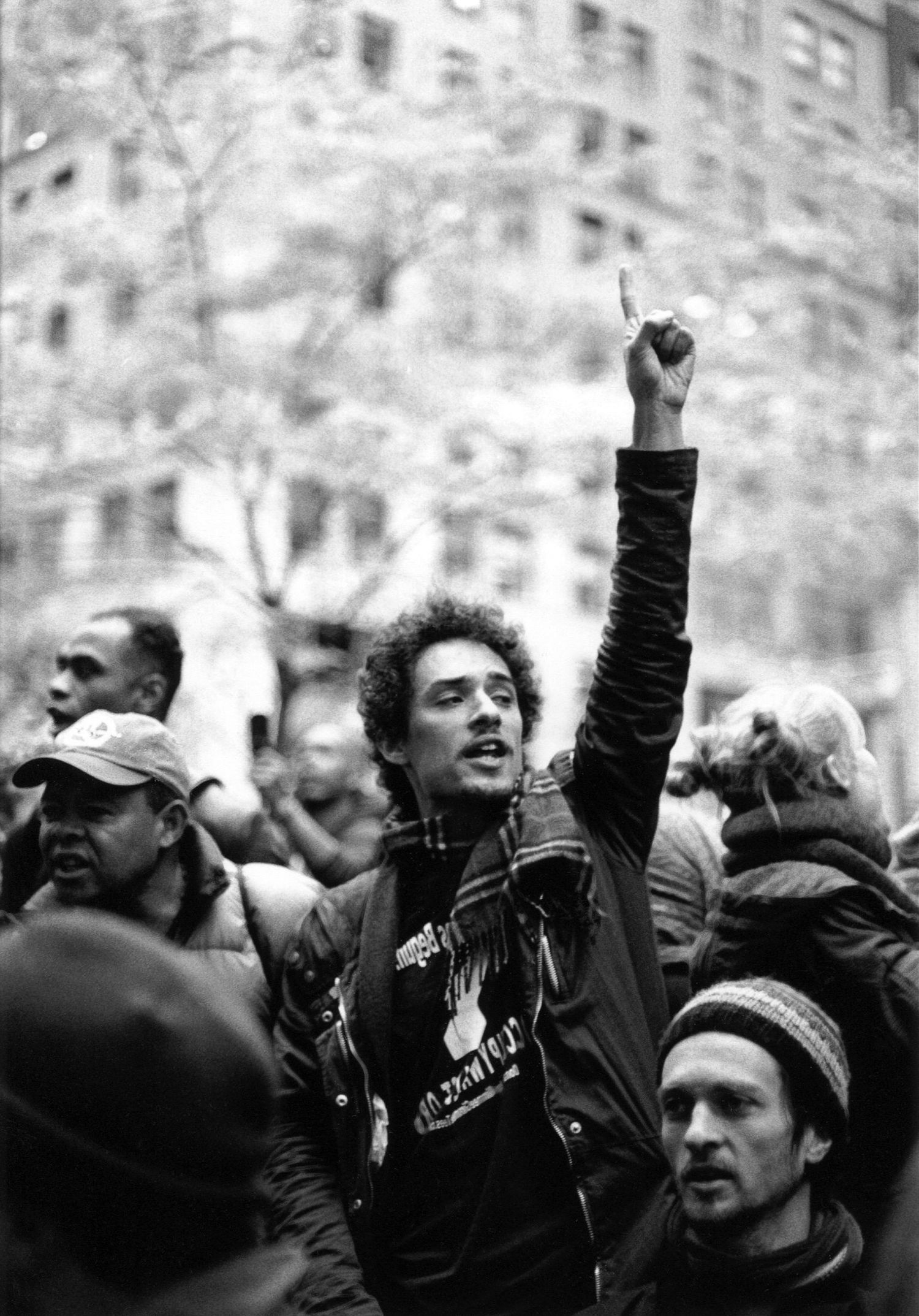 Black and white photo showing protesters raising their fists in solidarity during a demonstration.