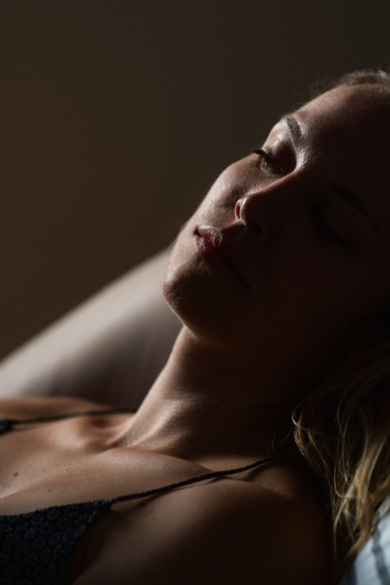 Artistic close-up profile portrait showing neck and jawline in dramatic lighting.