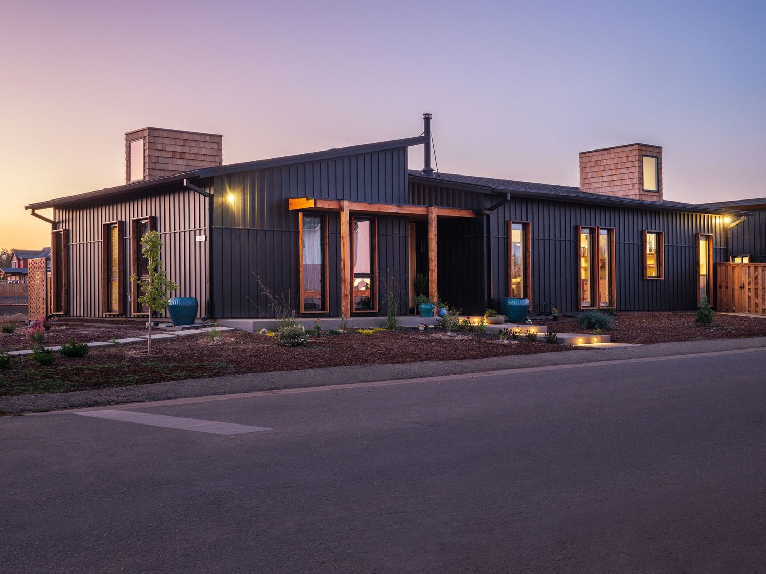 Twilight view of modern residential complex with warm interior lighting glowing through windows.