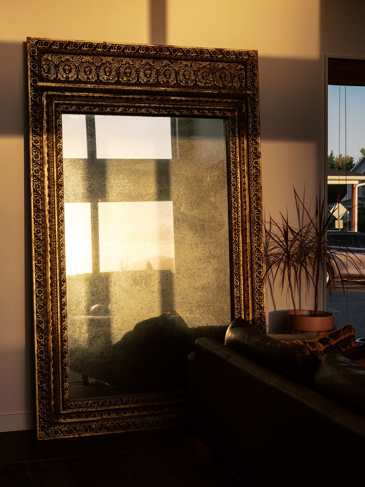 Ornate gold picture frames casting shadows on a wall during sunset.