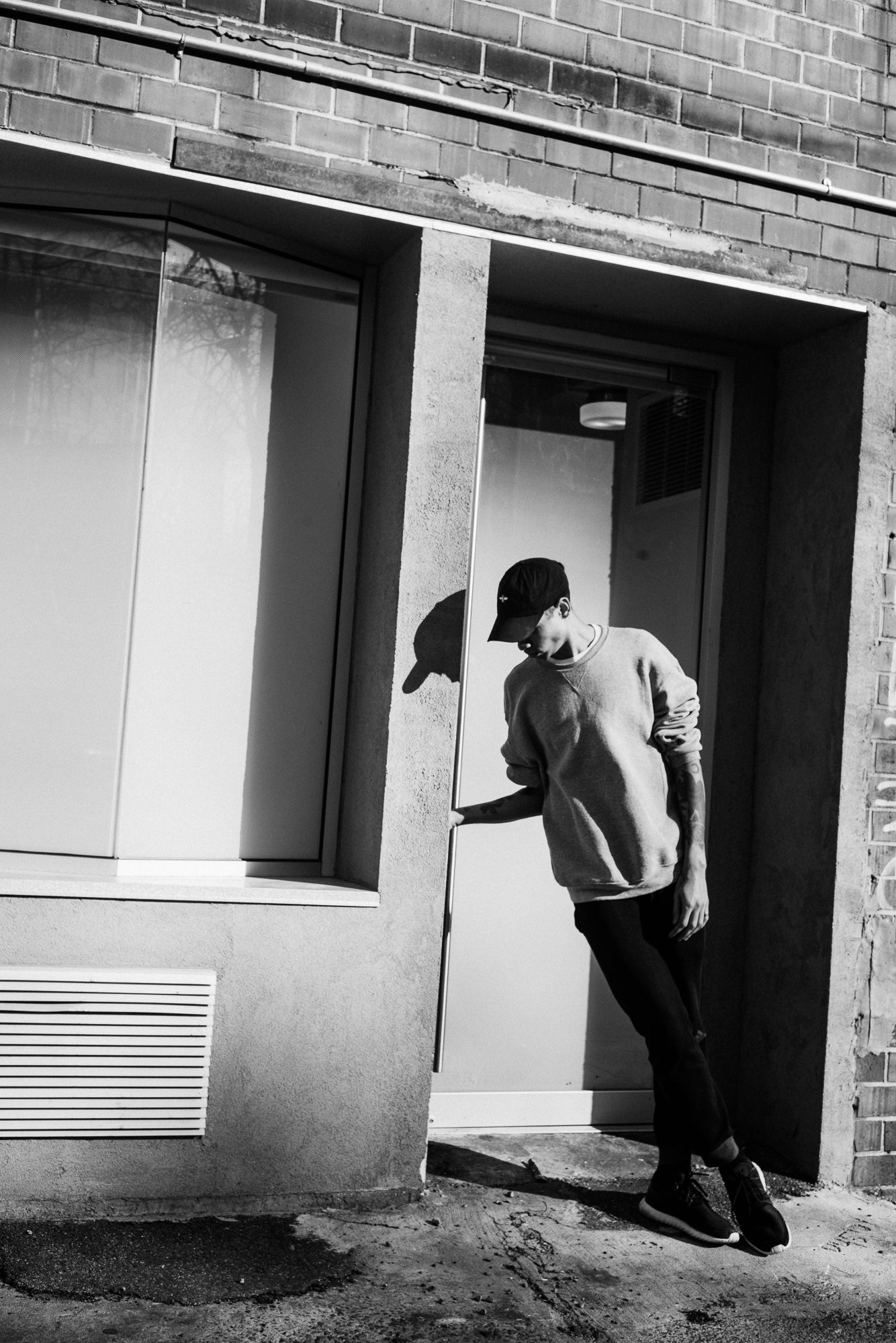 Black and white urban photo series showing figure crouching near brick building.