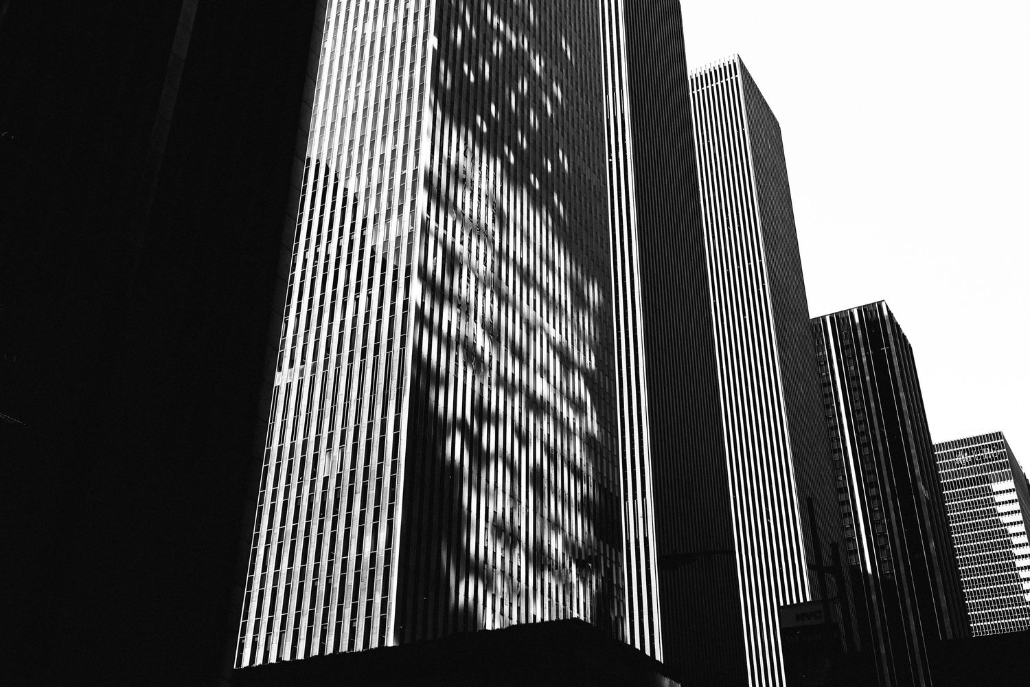 Dramatic black and white architectural photograph of modern skyscraper buildings with strong vertical lines against a dark sky.