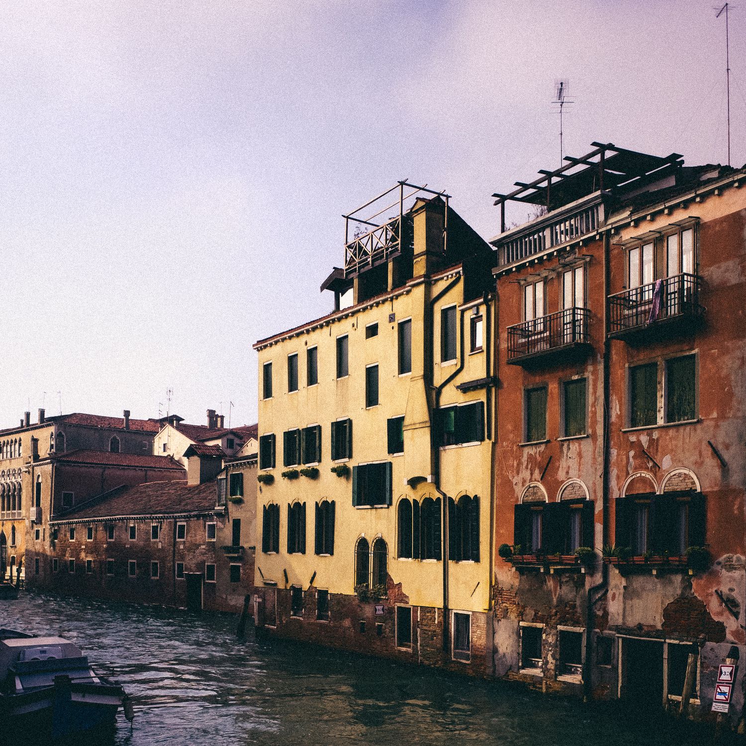 Row of colorful Italian buildings with traditional architecture line a flooded Venice canal during high tide.