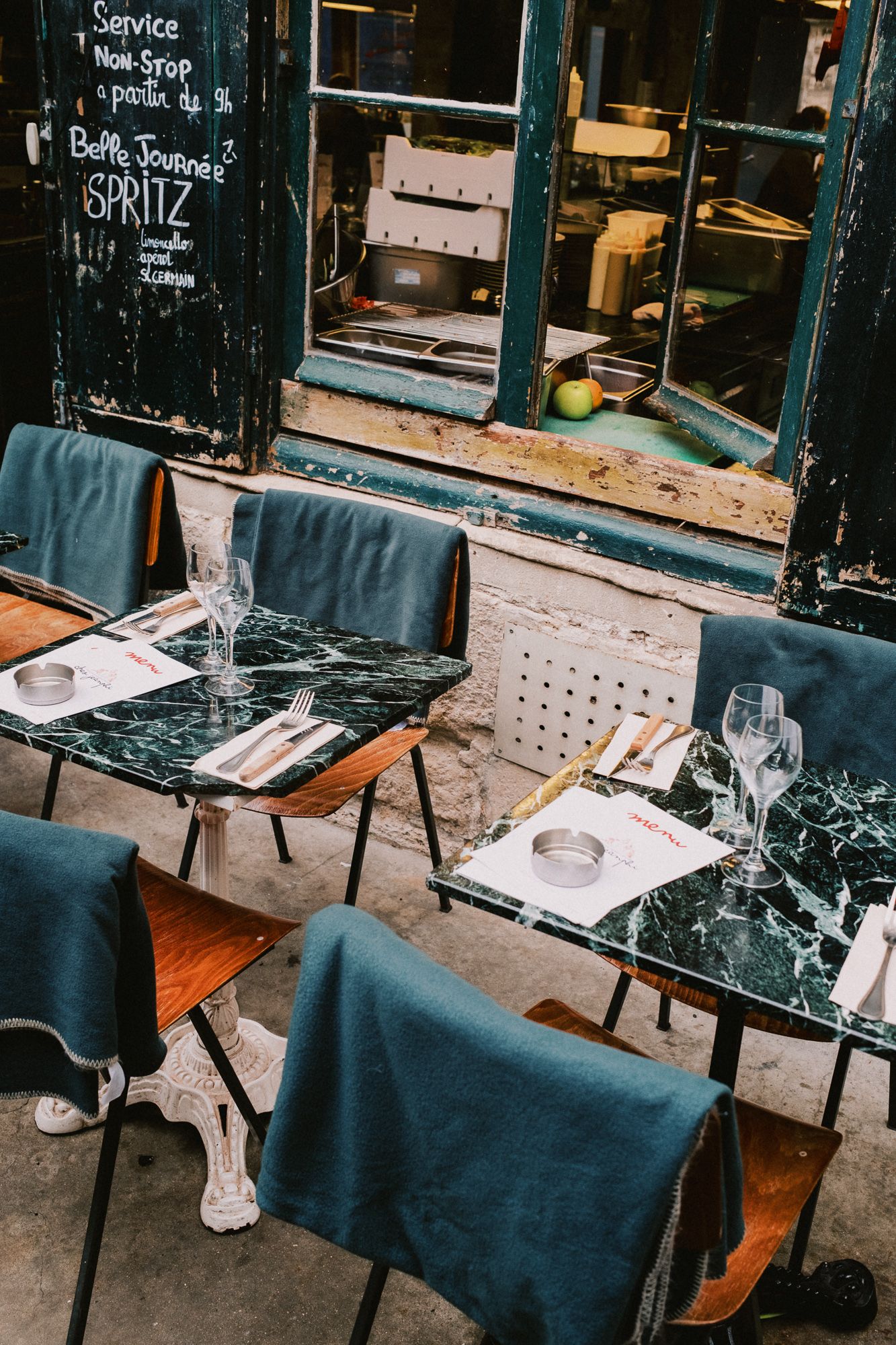 Restaurant tables set with dark tablecloths and wine glasses along a storefront.
