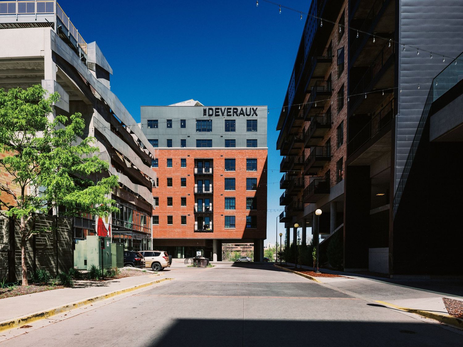 Red brick apartment buildings surrounding a paved courtyard under bright blue sky.