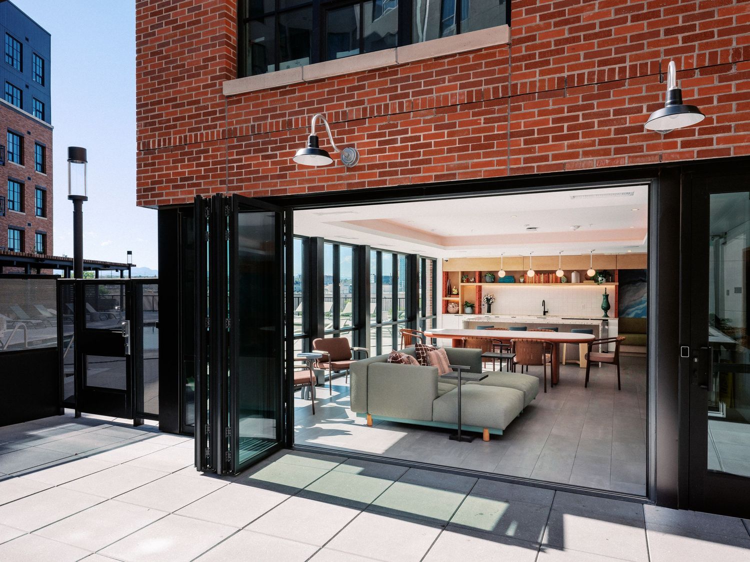 Modern brick building with folding glass doors opening to contemporary living space.