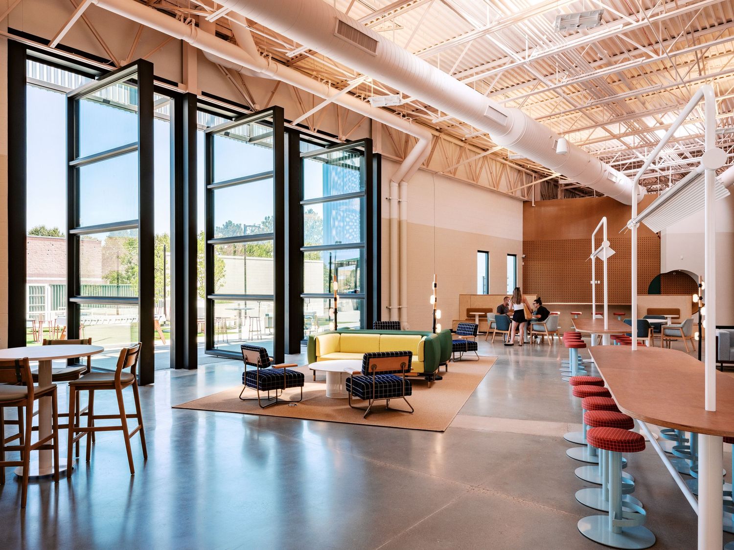 Spacious modern interior common area with high ceilings and natural lighting through large windows.