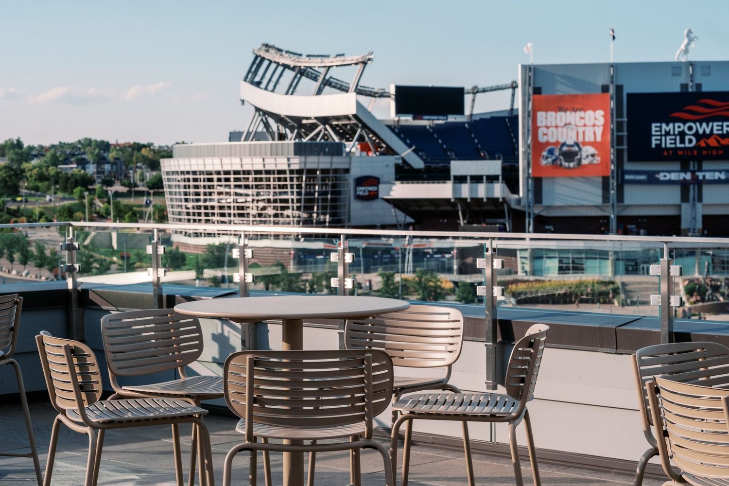 Outdoor rooftop seating area with chairs overlooking Empower Field at Mile High stadium in Denver.