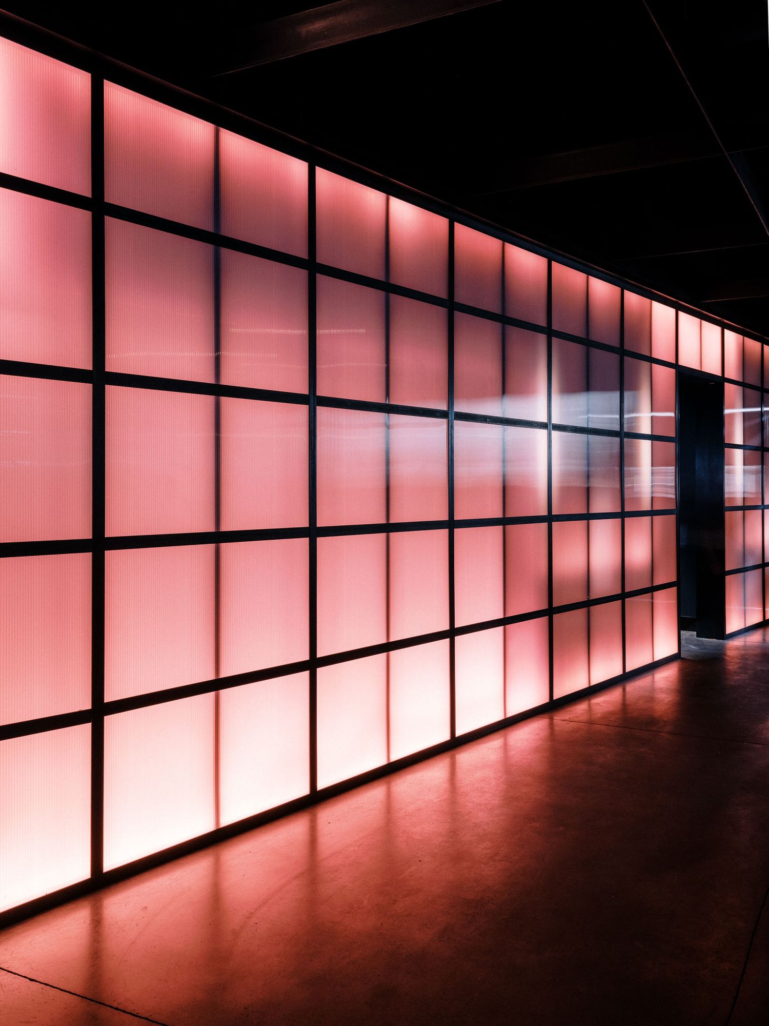 Long corridor with illuminated pink panels creating a dramatic perspective effect.