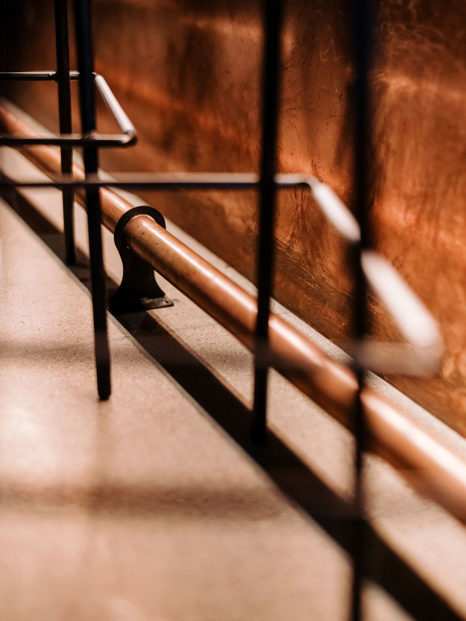 Abstract close-up of metal railings casting shadows in warm lighting.