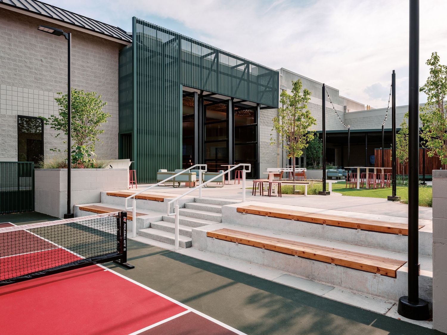 Modern building entrance with red walkway and concrete steps leading to glass doors.