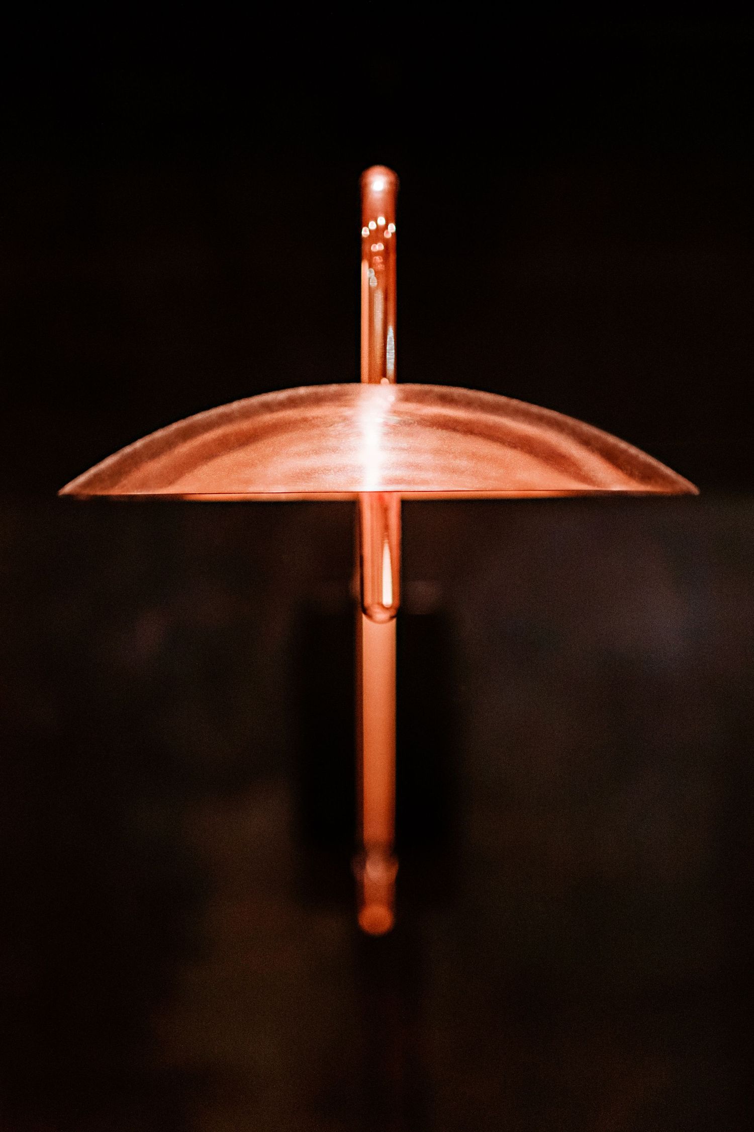Glowing orange cross-shaped light fixture mounted on a dark wall creates dramatic illumination.