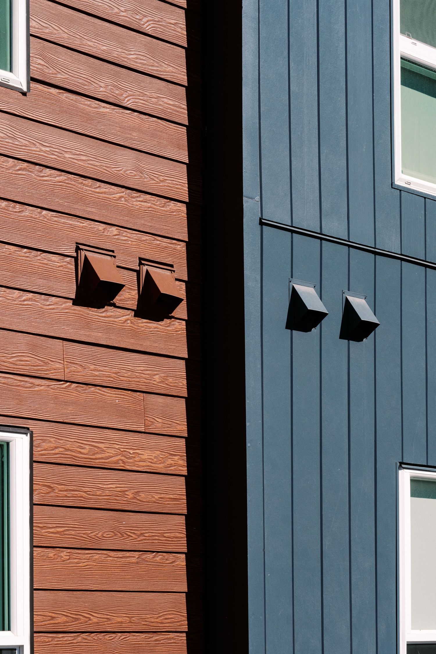 Exterior wall detail showing alternating brown wood panels and blue shutters.