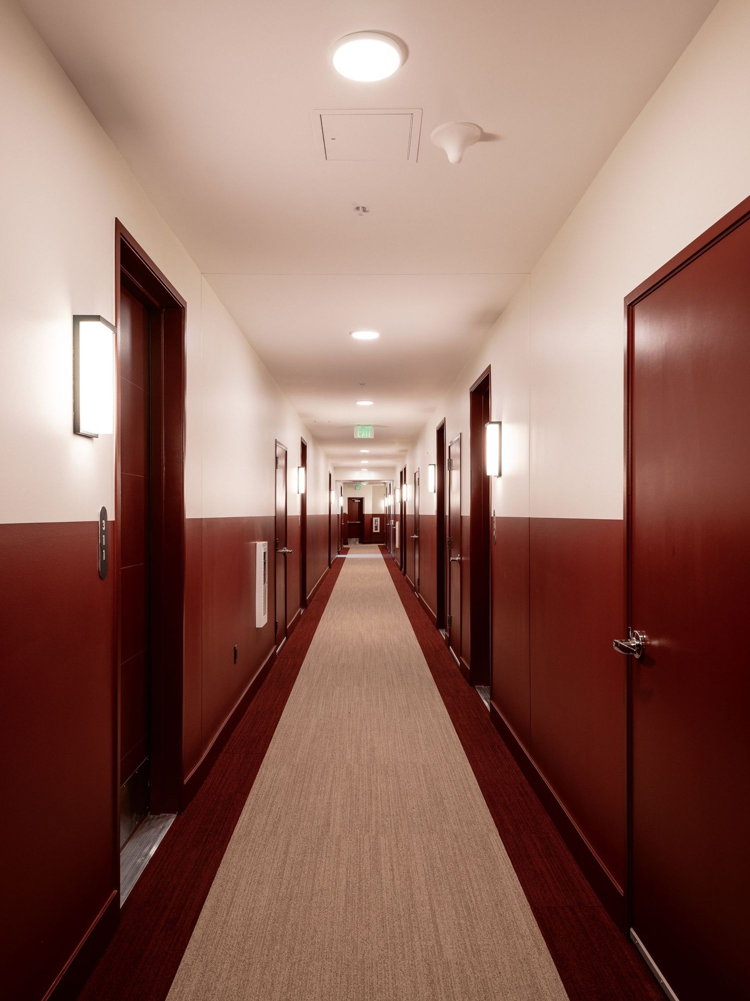 Long minimalist hallway with burgundy walls and recessed lighting.