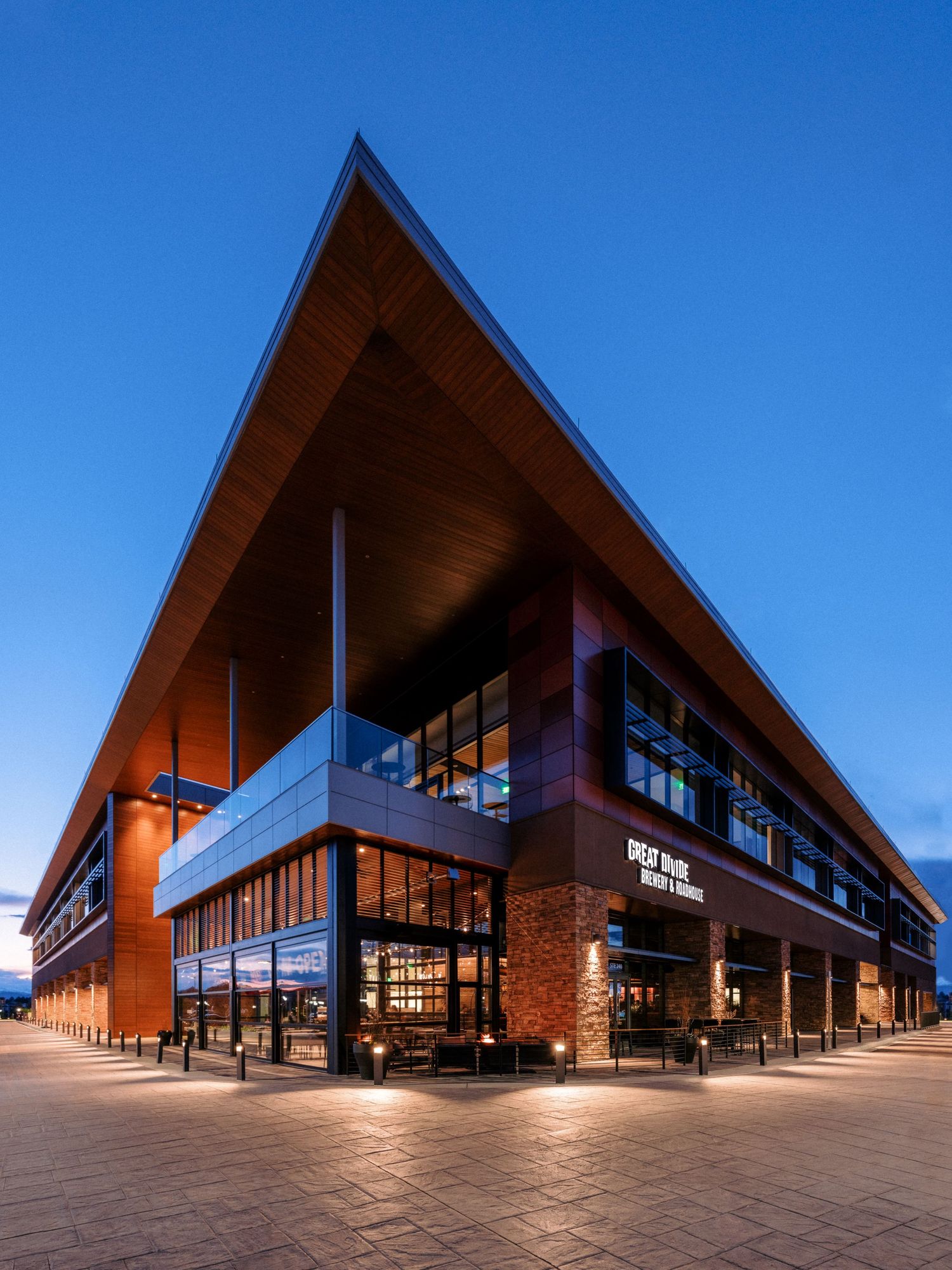 Modern commercial building exterior with angular roof and brick facade under bright blue sky.
