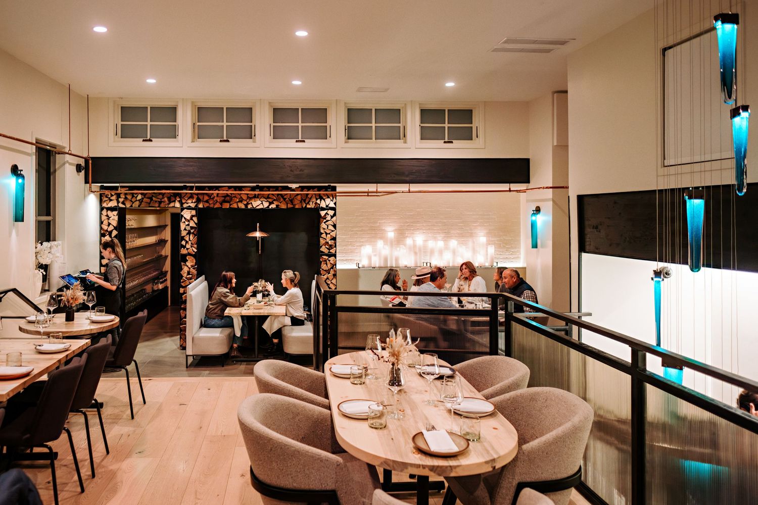 Sophisticated restaurant interior with curved booth seating and turquoise accent lighting.