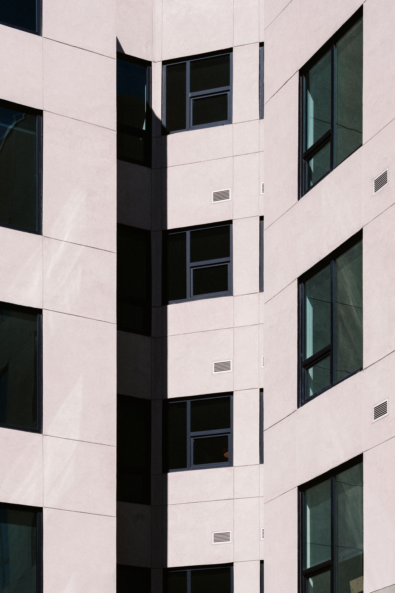 Abstract architectural detail of white building facade with geometric window patterns.