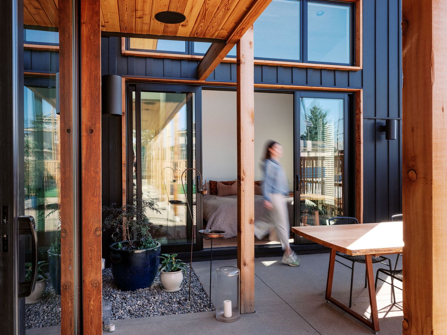 Contemporary open-concept living space with wooden beams and floor-to-ceiling windows.