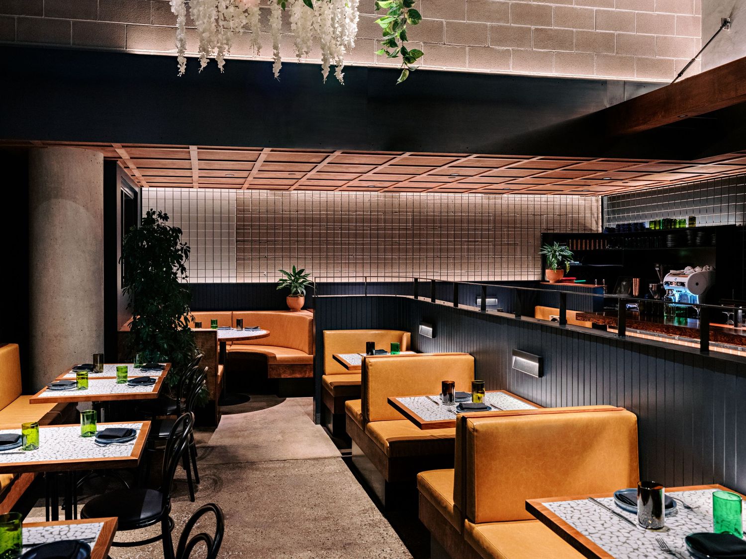 Restaurant interior with tan leather booths and modern decor under ambient lighting.