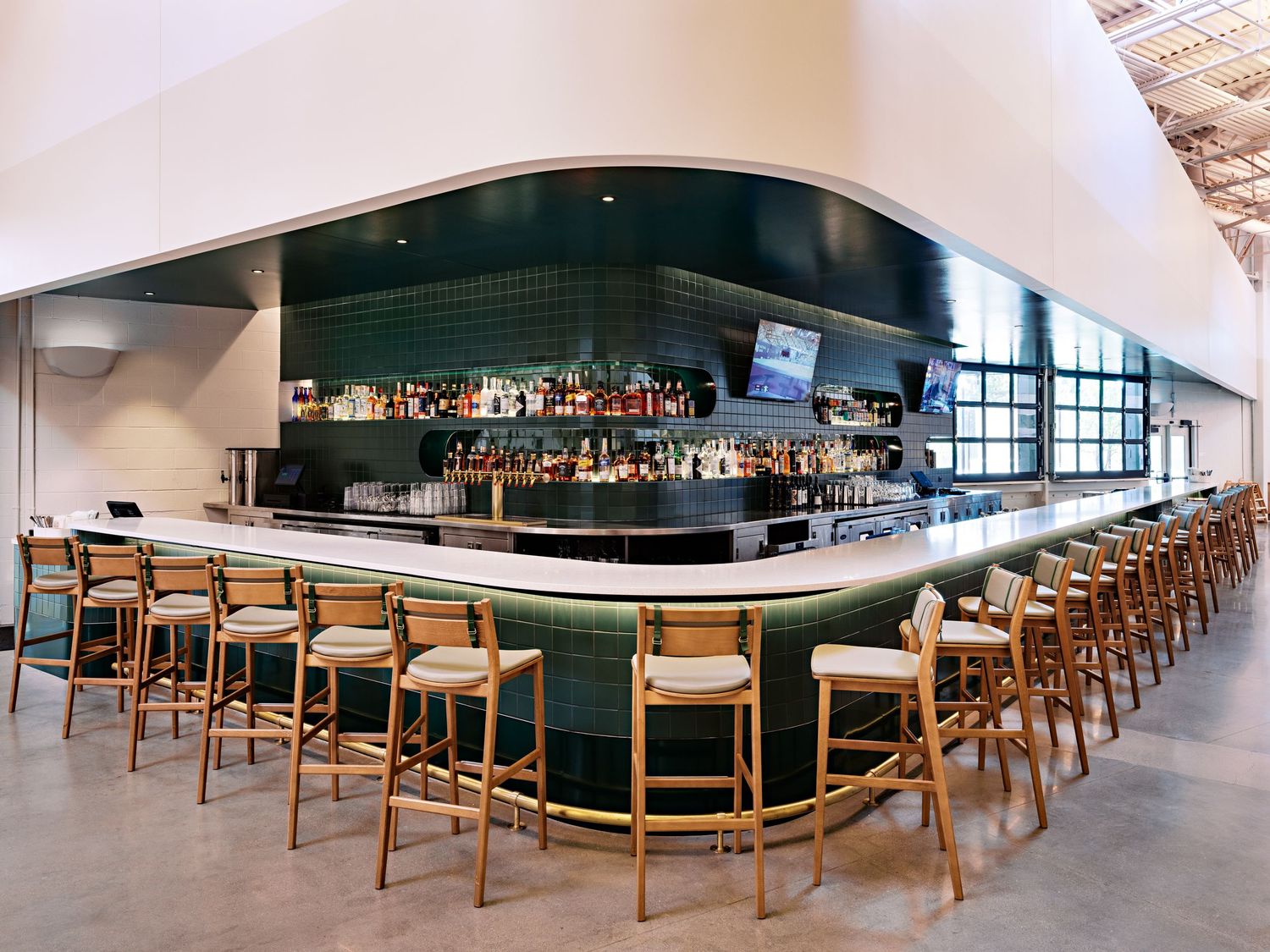 Panoramic view of an upscale bar area with wooden chairs and curved seating arrangements.