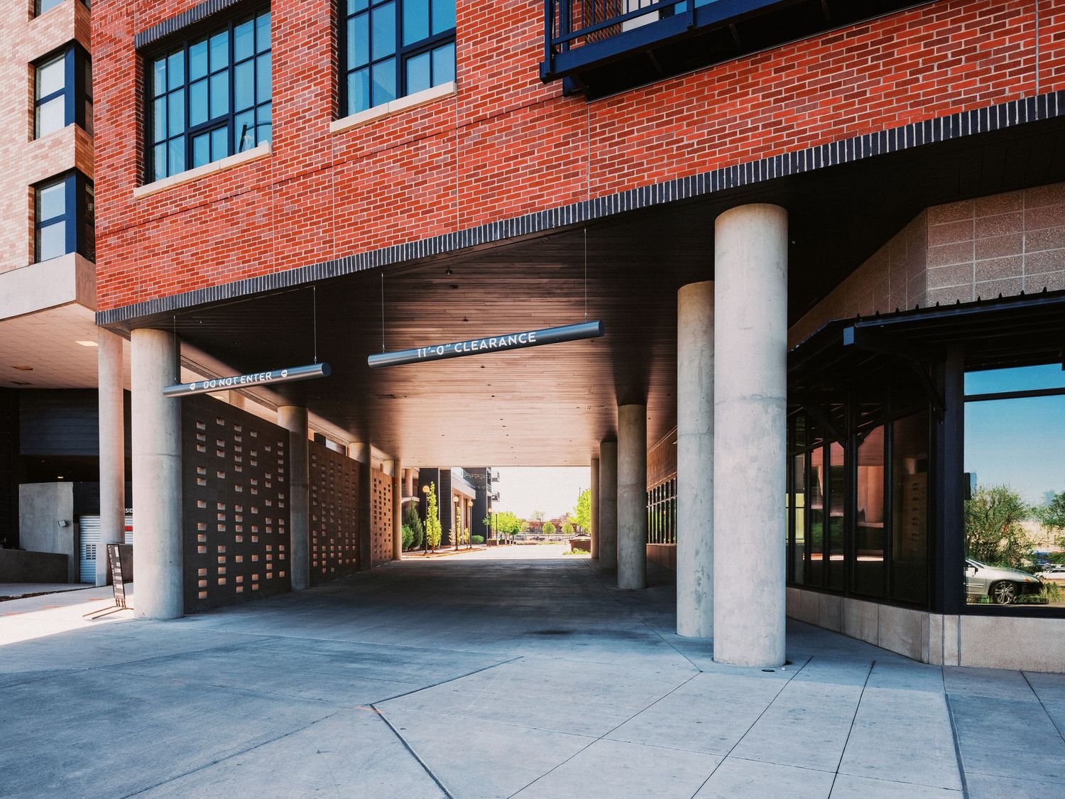 Modern brick building exterior with large windows and concrete columns creating covered walkways.