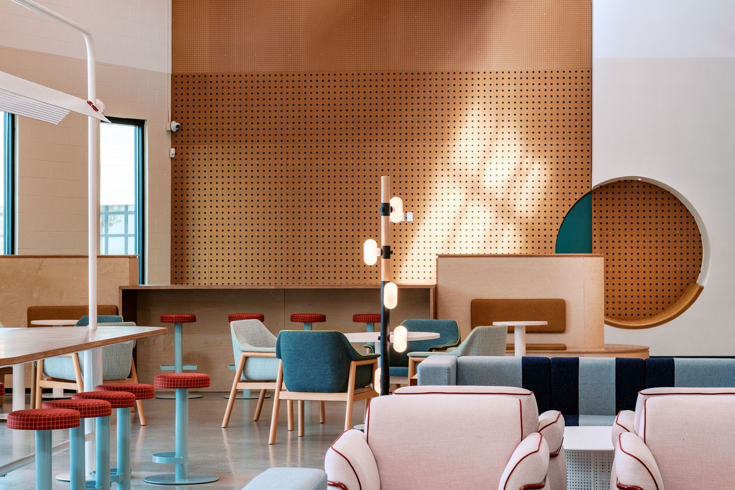 Modern cafe interior with peach walls, blue chairs and geometric design elements.